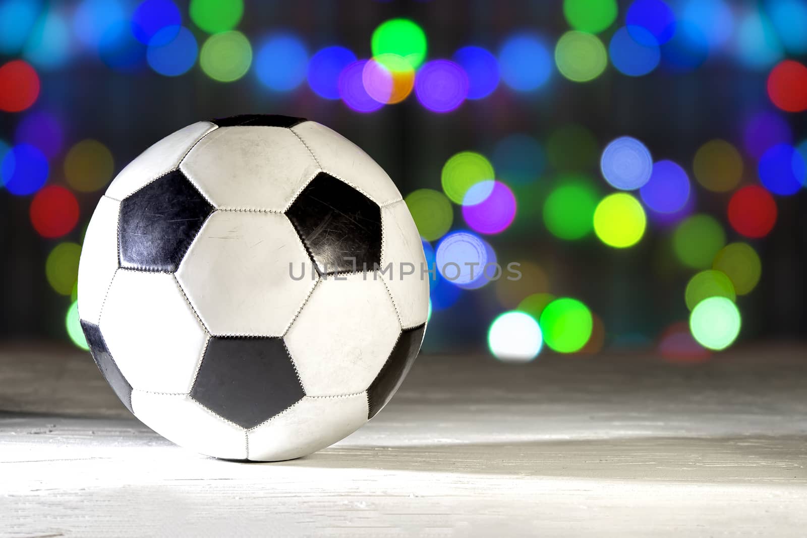 Football soccer on a white texture surface with a hard shadow on a colourful bokeh of lights on December. by oasisamuel