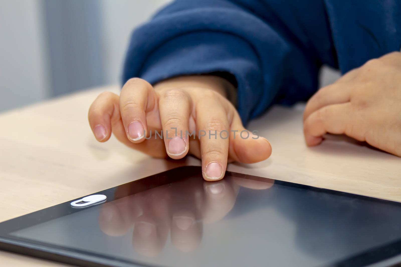 Close up front view of a little boy's hand using and tablet during the day time by oasisamuel