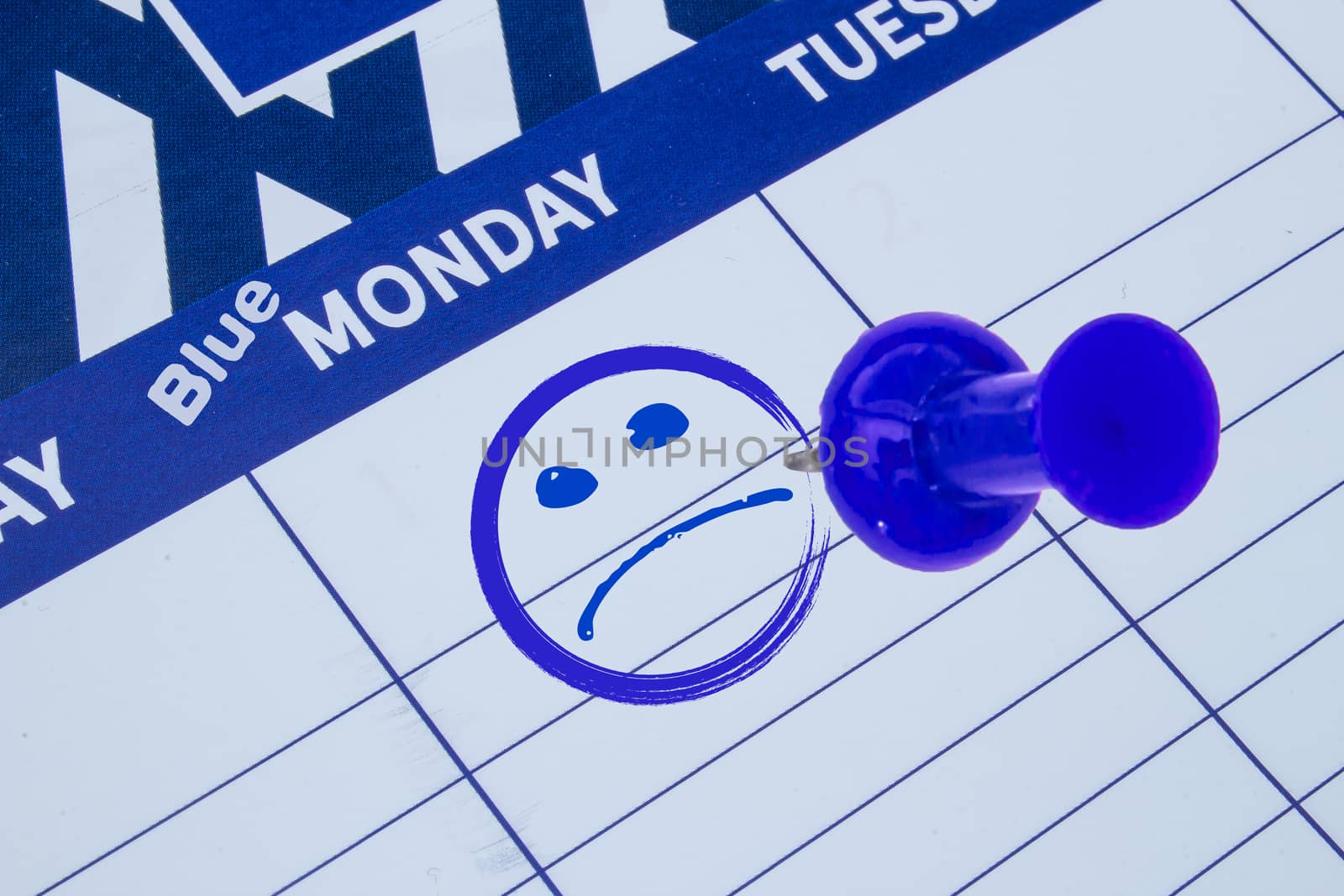 A close up on a calendar on focus on a Blue Monday with a Sad face and blue pin by oasisamuel