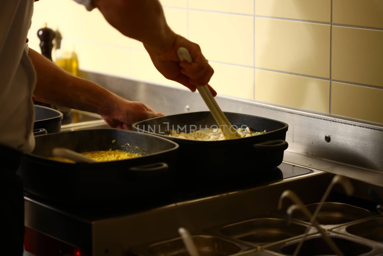professional cook in kitchen preparing food for customers showing hands stirring food in pot