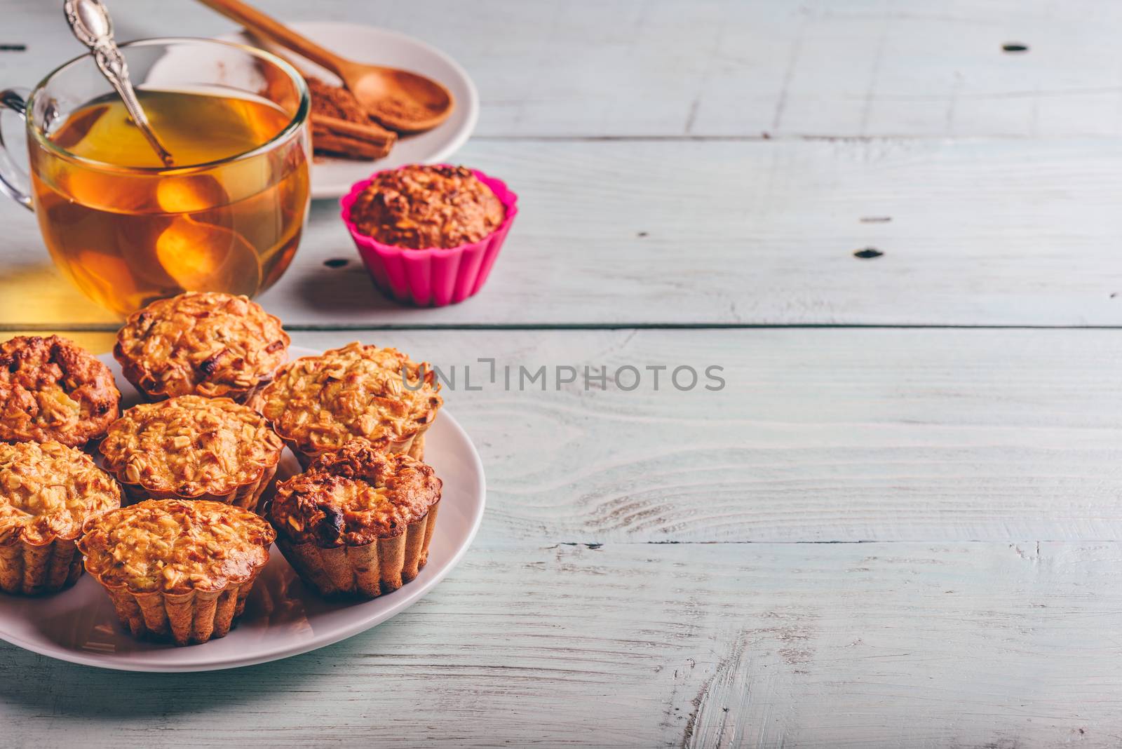 Healthy Dessert. Oatmeal muffins with cup of green tea over light wooden background. Copy Space.