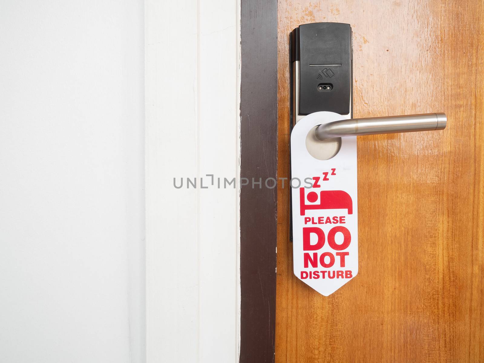 Do not disturb sign attached to the front of the room that is closed inside the hotel on the wooden door with stainless steel handles and use the electronic key system.