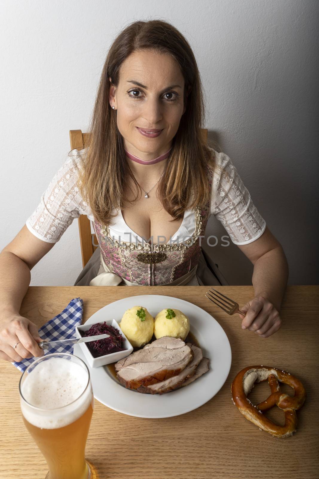 woman with a dirndl eating roasted pork