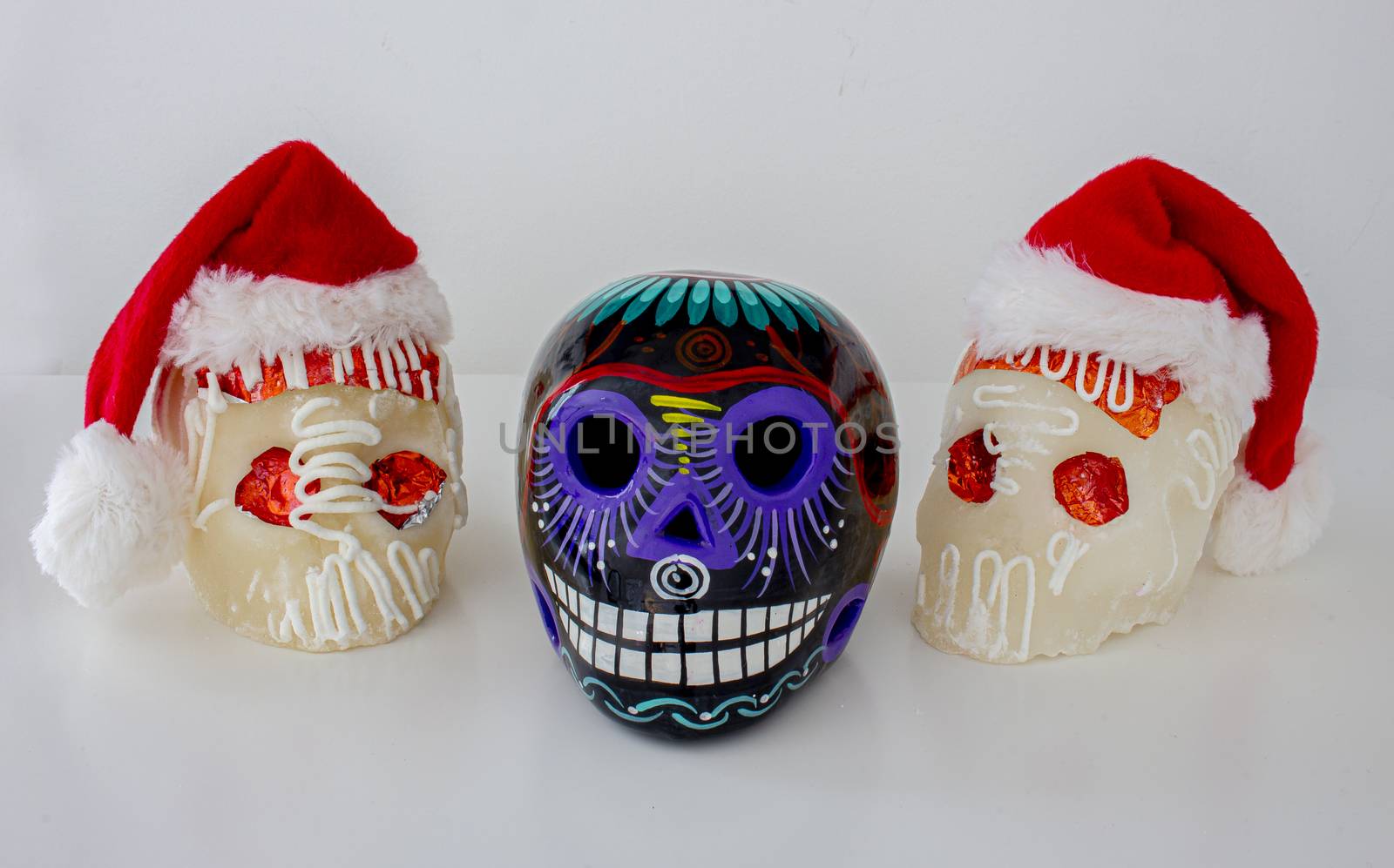 White Traditional Mexican sugar skulls with Santa hats. Mexican Christmas.(calaveritas de azucar para navidad en México) mix cultures.
