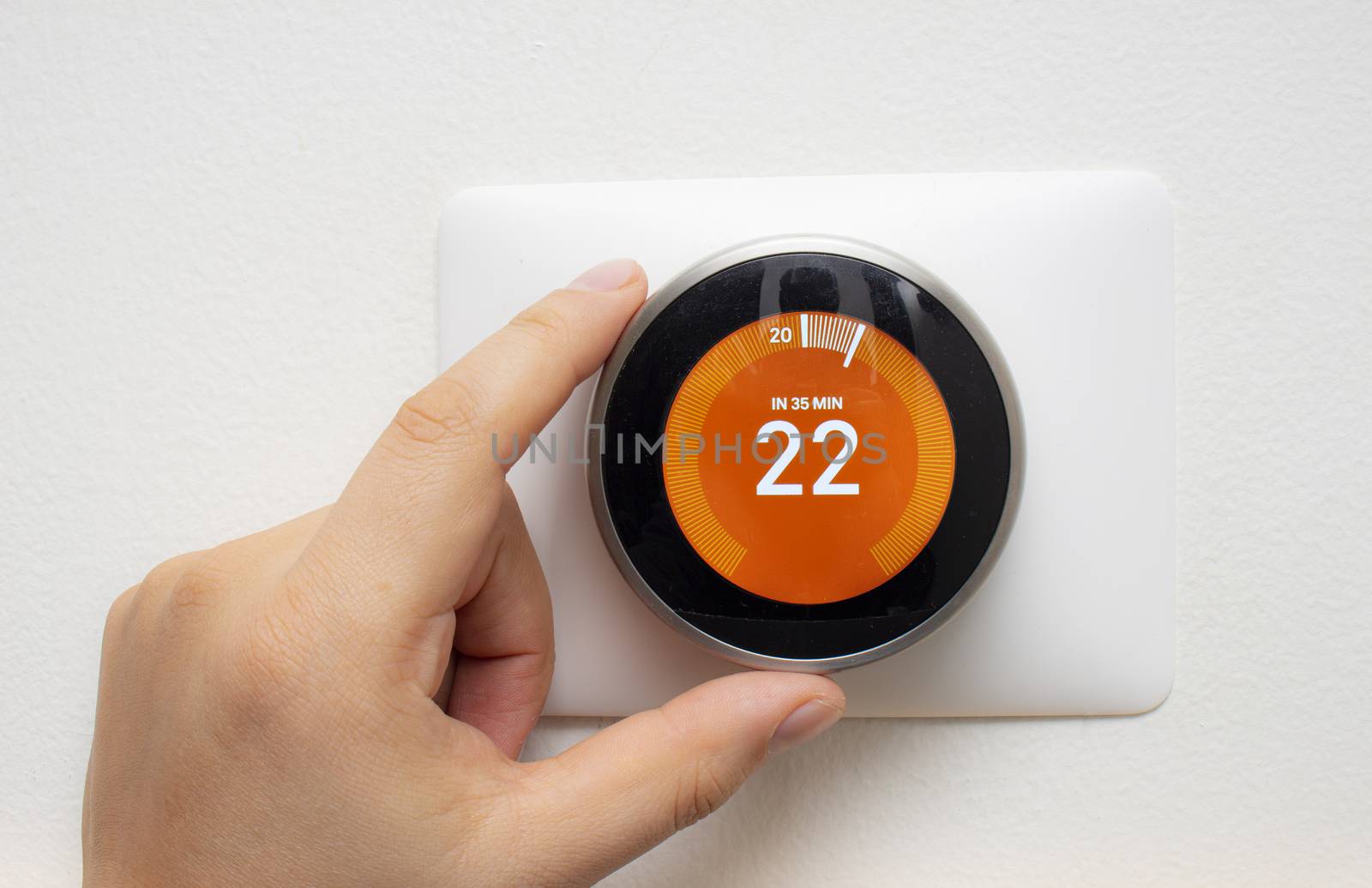 Smart Thermostat with a person warming up the room temperature with a soft shadow by oasisamuel