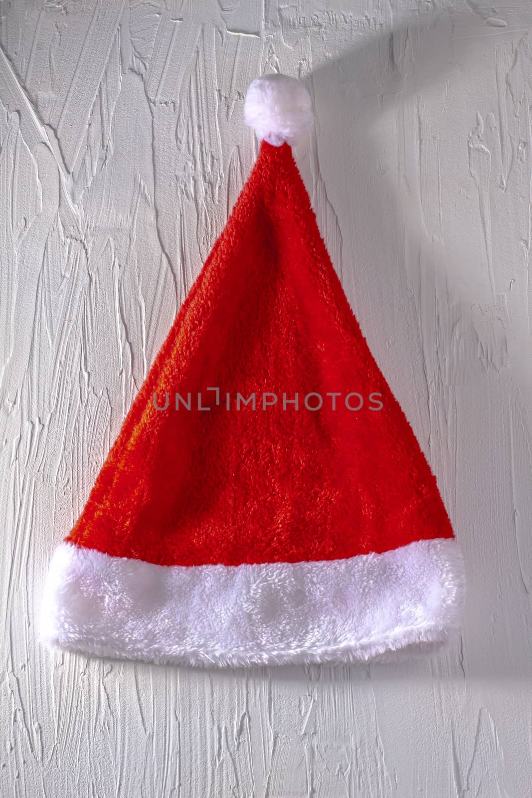 Santa Claus hat on white texture background with a shadow by oasisamuel