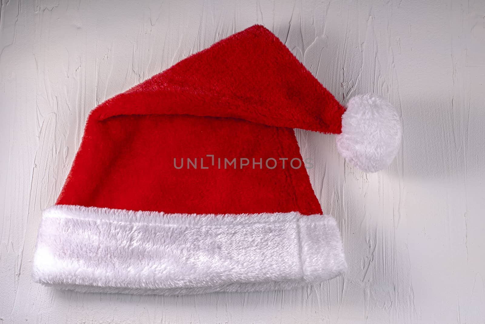 Folded Christmas Santa hat on a white texture background by oasisamuel