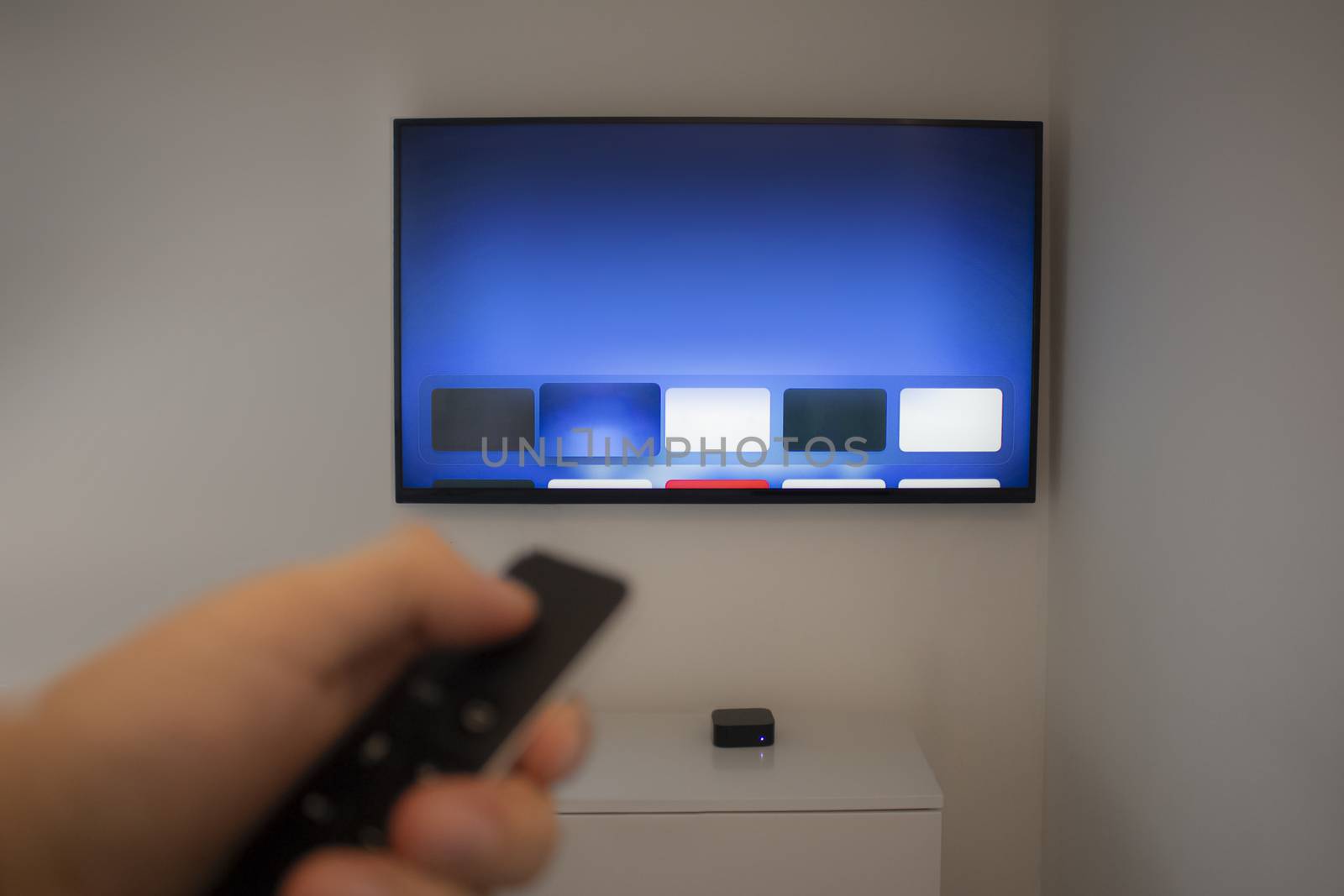 Person holds TV remote using a generic application on a smart TV. by oasisamuel