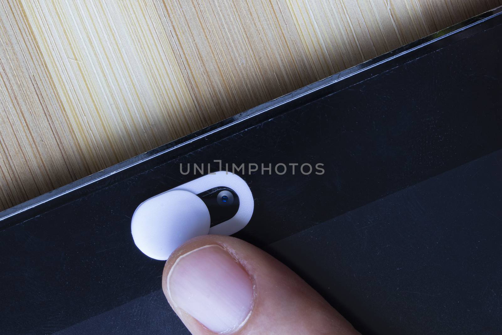 A White Color Camera Privacy Cover. Slide Webcam. Cover for an electronic device with a finger.