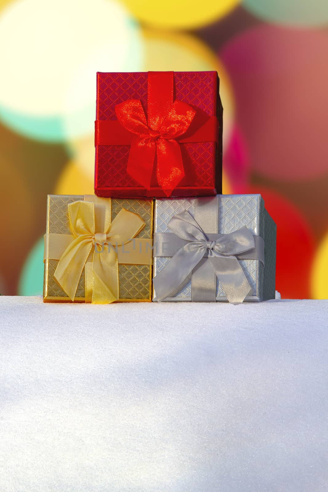 Colourful Gift boxes Presents on snow with a bokeh Background on a vertical view by oasisamuel