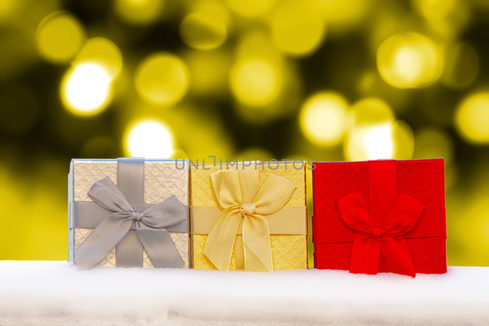 Colourful Gif boxes Presents on snow with golden christmas lights on the Background by oasisamuel