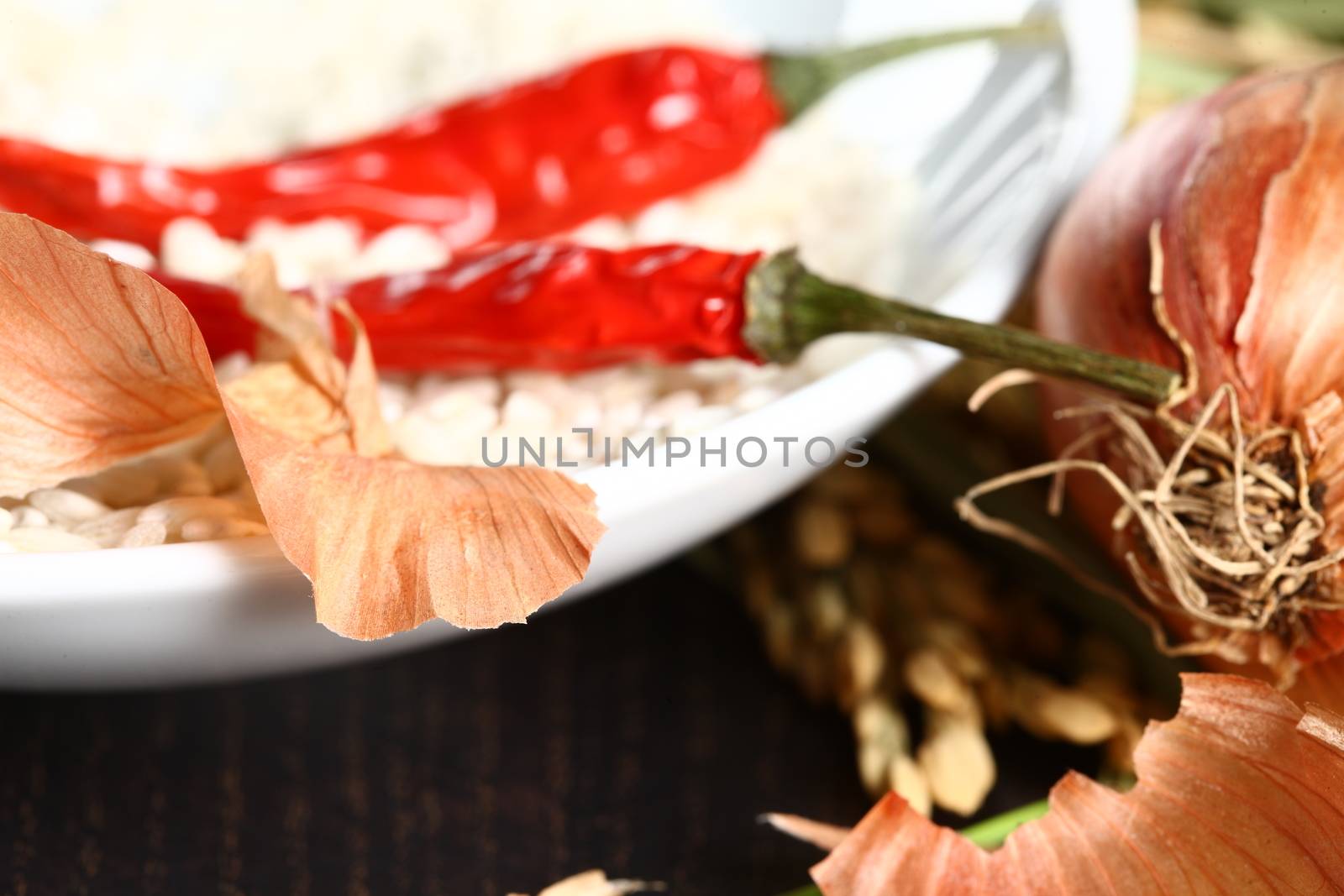 Healthy organic raw food ready for cooking. Close up of onion peel with rice corn laying on a table with a white plate