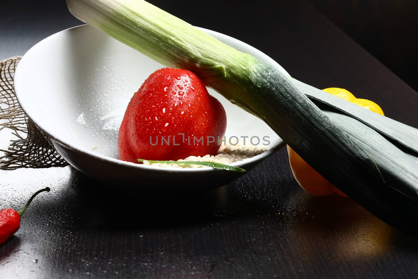 Healthy fresh organic food with water drops with rice and red and yellow pepperoni and green leek