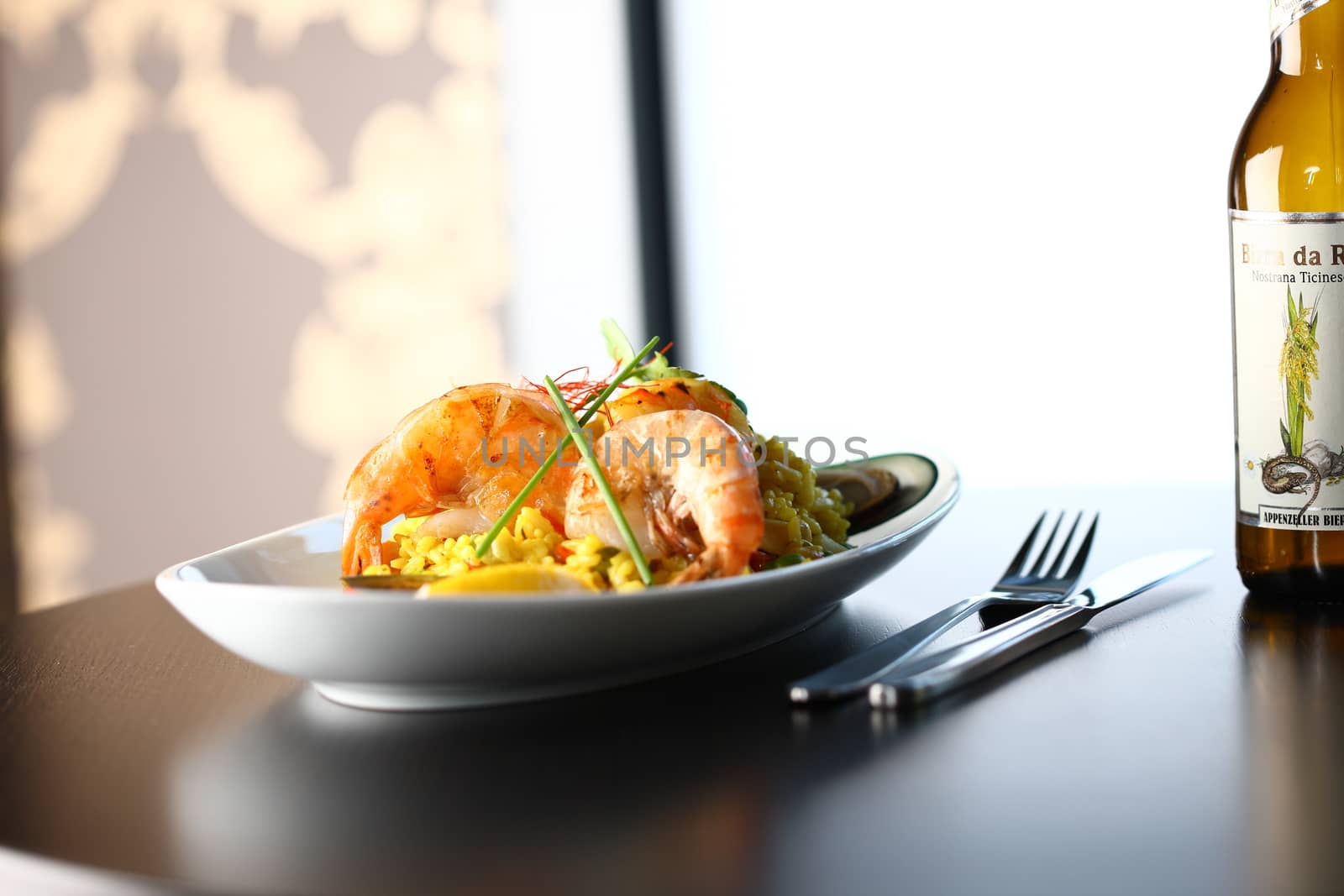 dish with shrimp and vegetable on a table top with light background with fork and knife