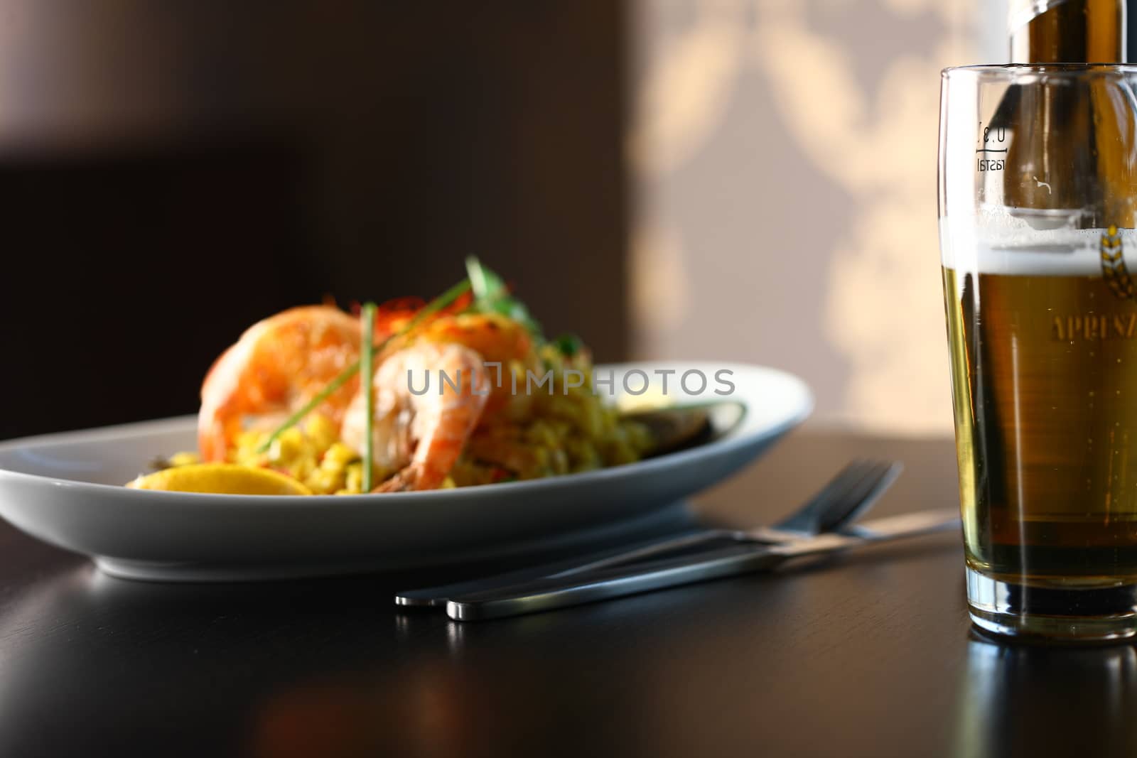 dish with shrimp and salad and a glass of beer in foreground