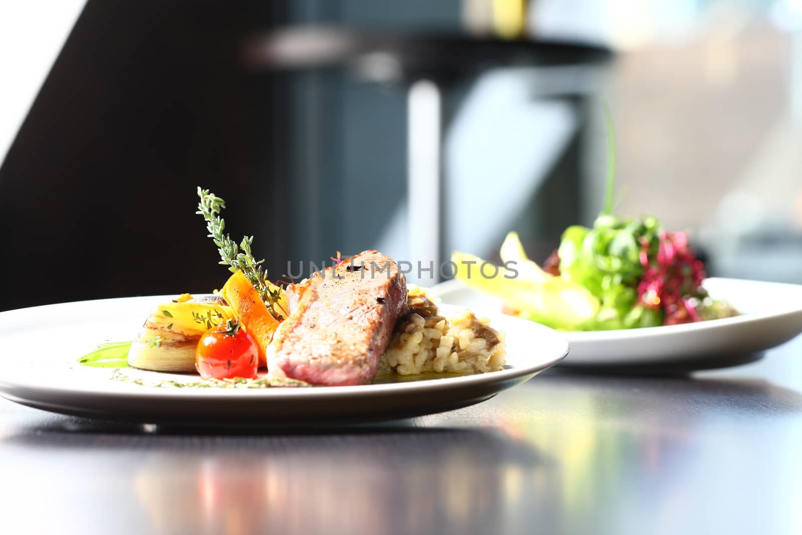 a good meal with meat and salad on white plates with restaurant setting