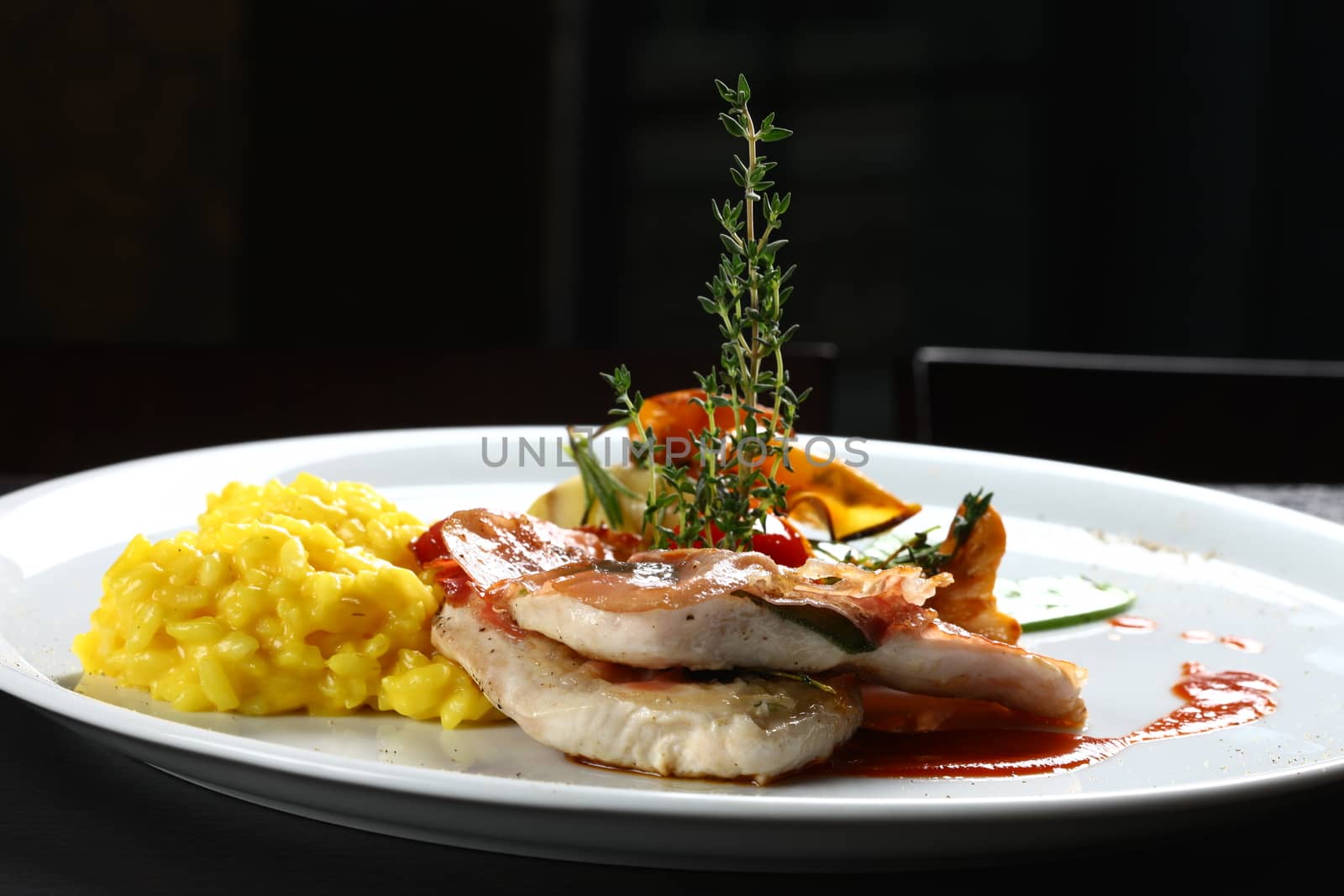 Extreme close up of dish with meat, yellow rice, mushrooms. Nice display of gourmet food. with a black background