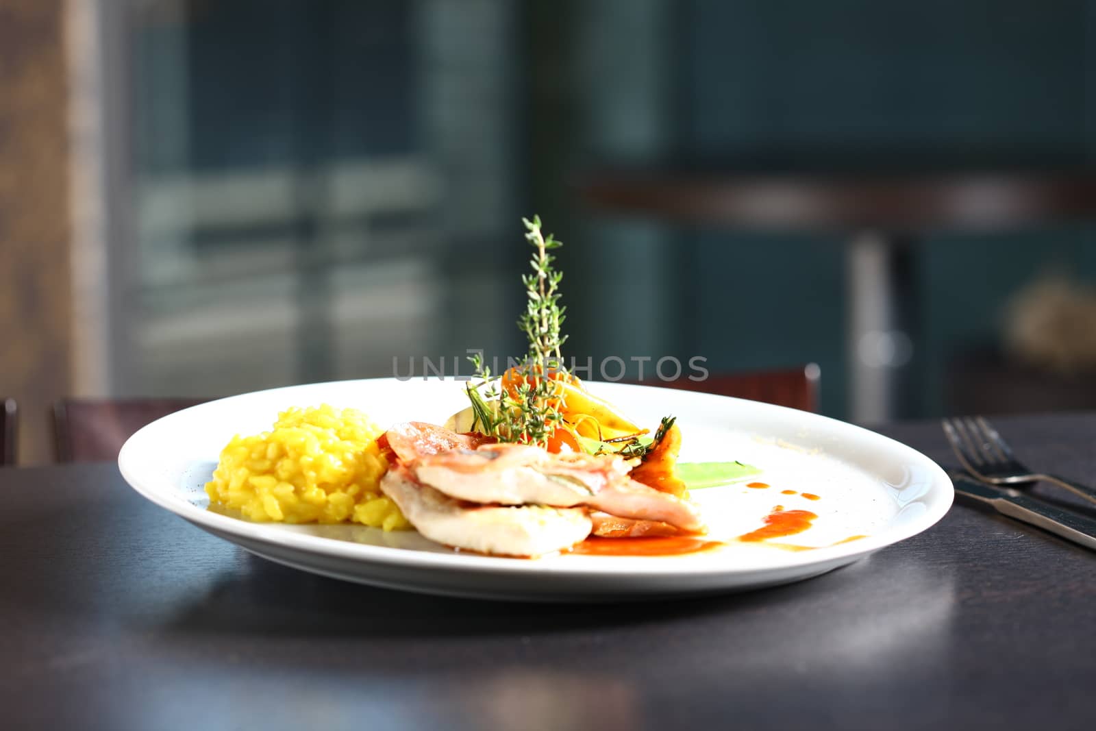 Extreme close up of dish with meat, yellow rice, mushrooms. Nice display of gourmet food. With a windows in the background