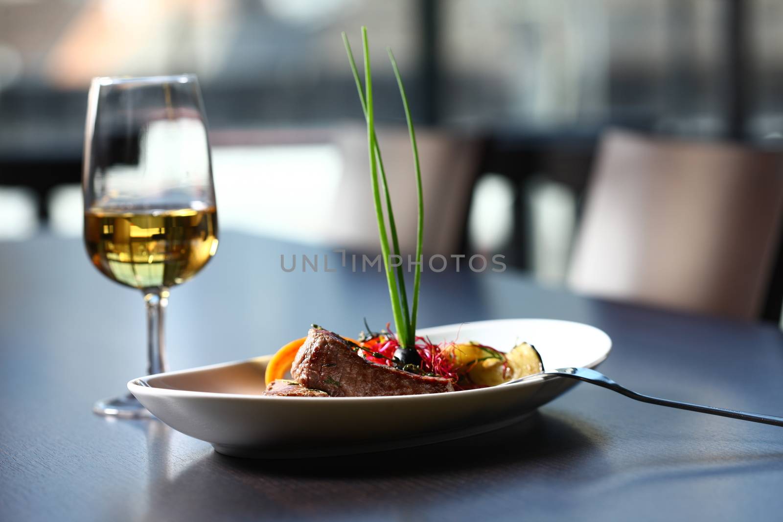 a good meal with wine. close up of a dish with meal, rice and mushrooms and a glass of wine in background . On clean grey table with chair showing in the background