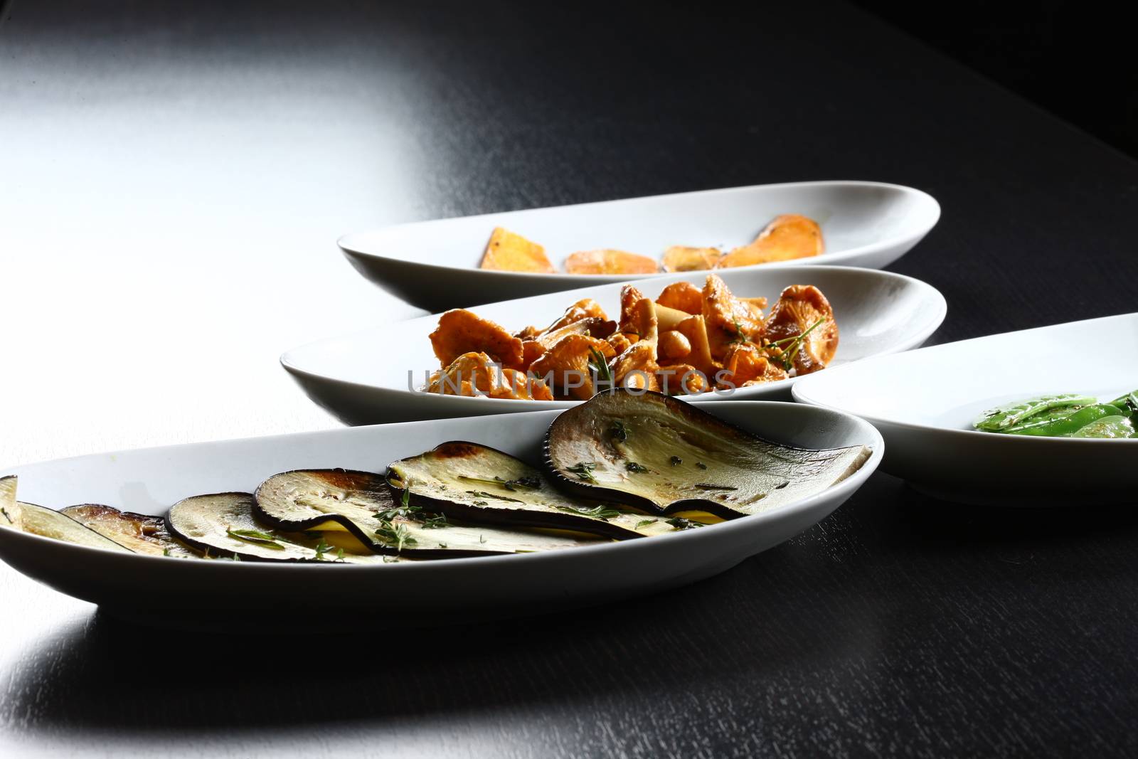 food white plates on table top, ready to served for guests in a dark setting. Mushrooms and leek cooked
