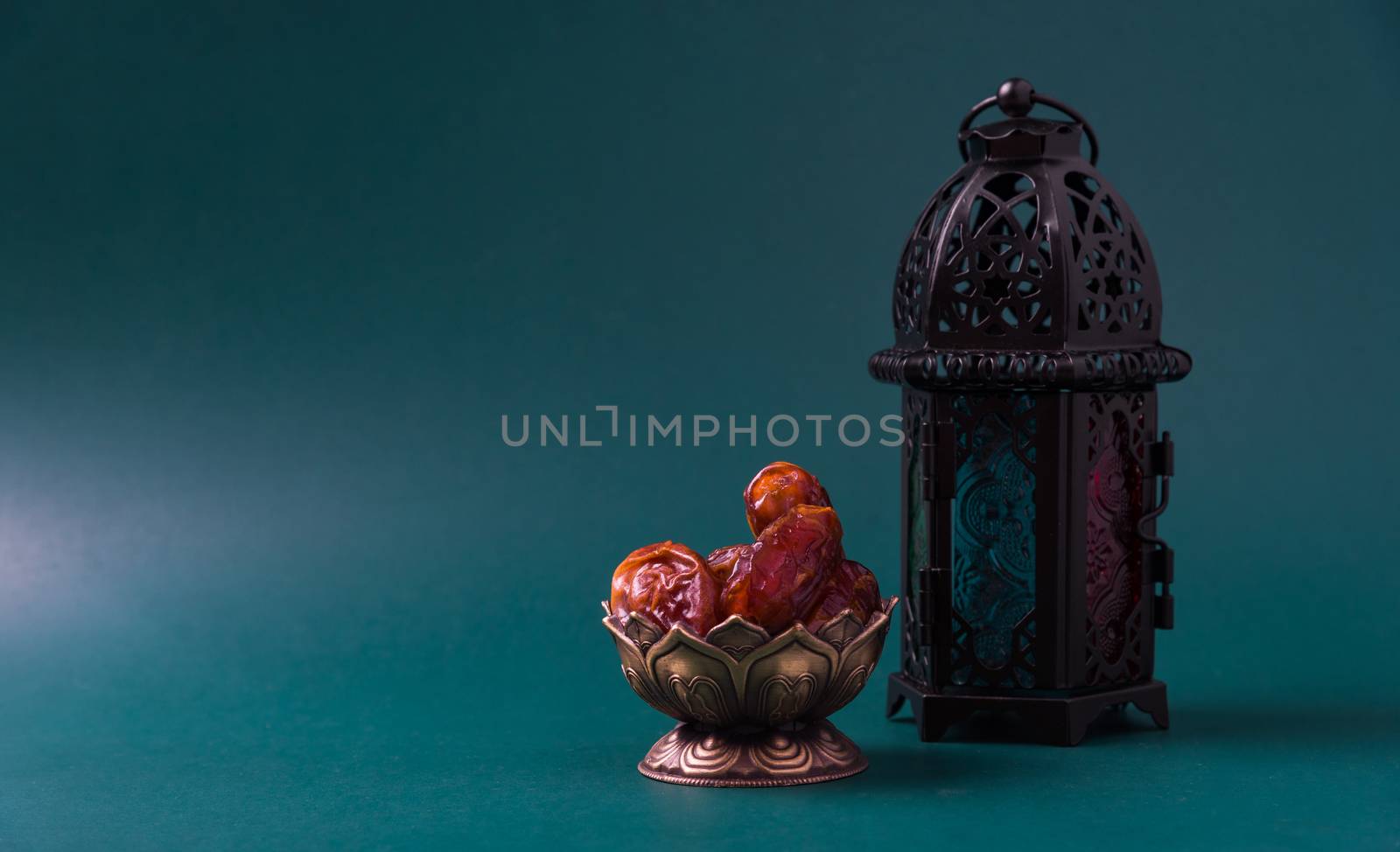 Ramadan Kareem fasting Food Concept, Bronze plate dates, and lantern Aladdin lamp decoration, eid Arabian Muslim religious festival on a dark green background with copy space for text