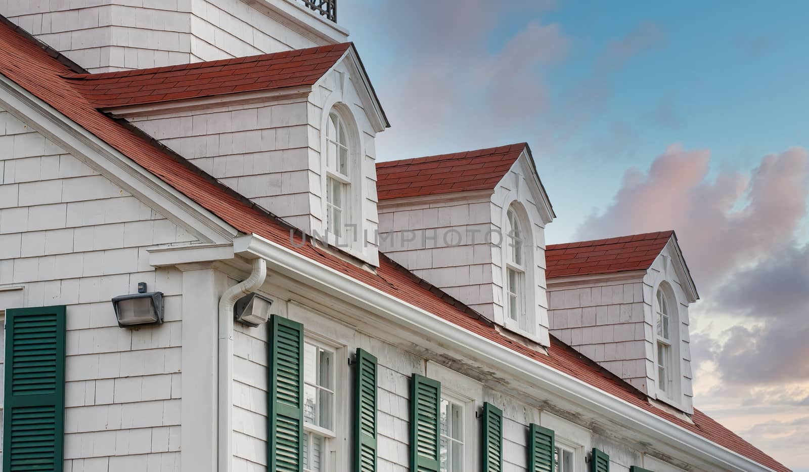 Large coastal home of white wood with a red roof