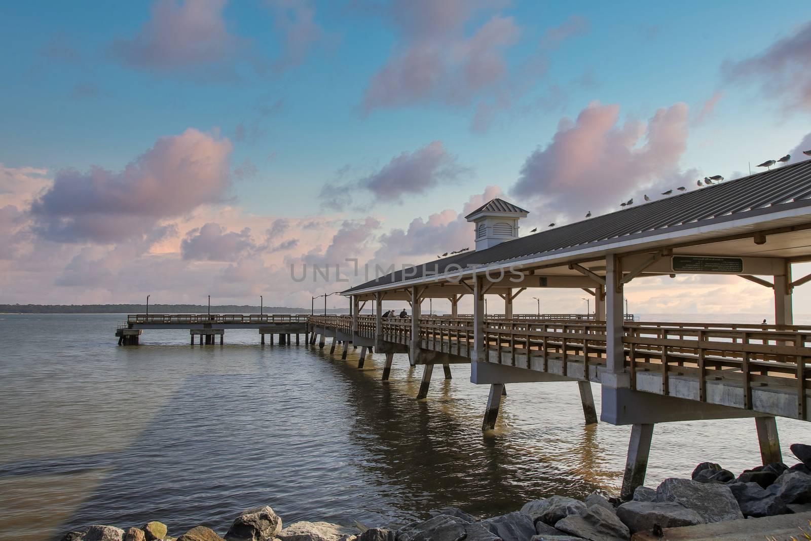 An old wooden and concrete pier jutting out into a calm bay