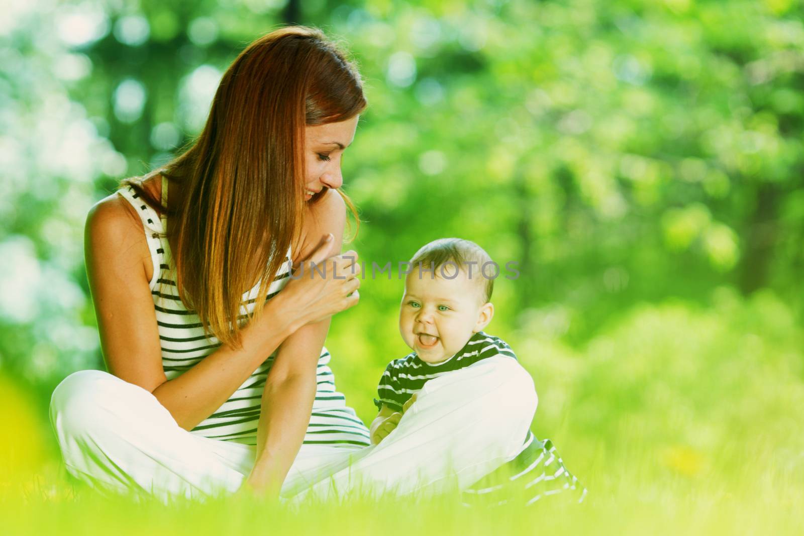 Happy mother and daughter relaxing sitting on grass background spring meadow