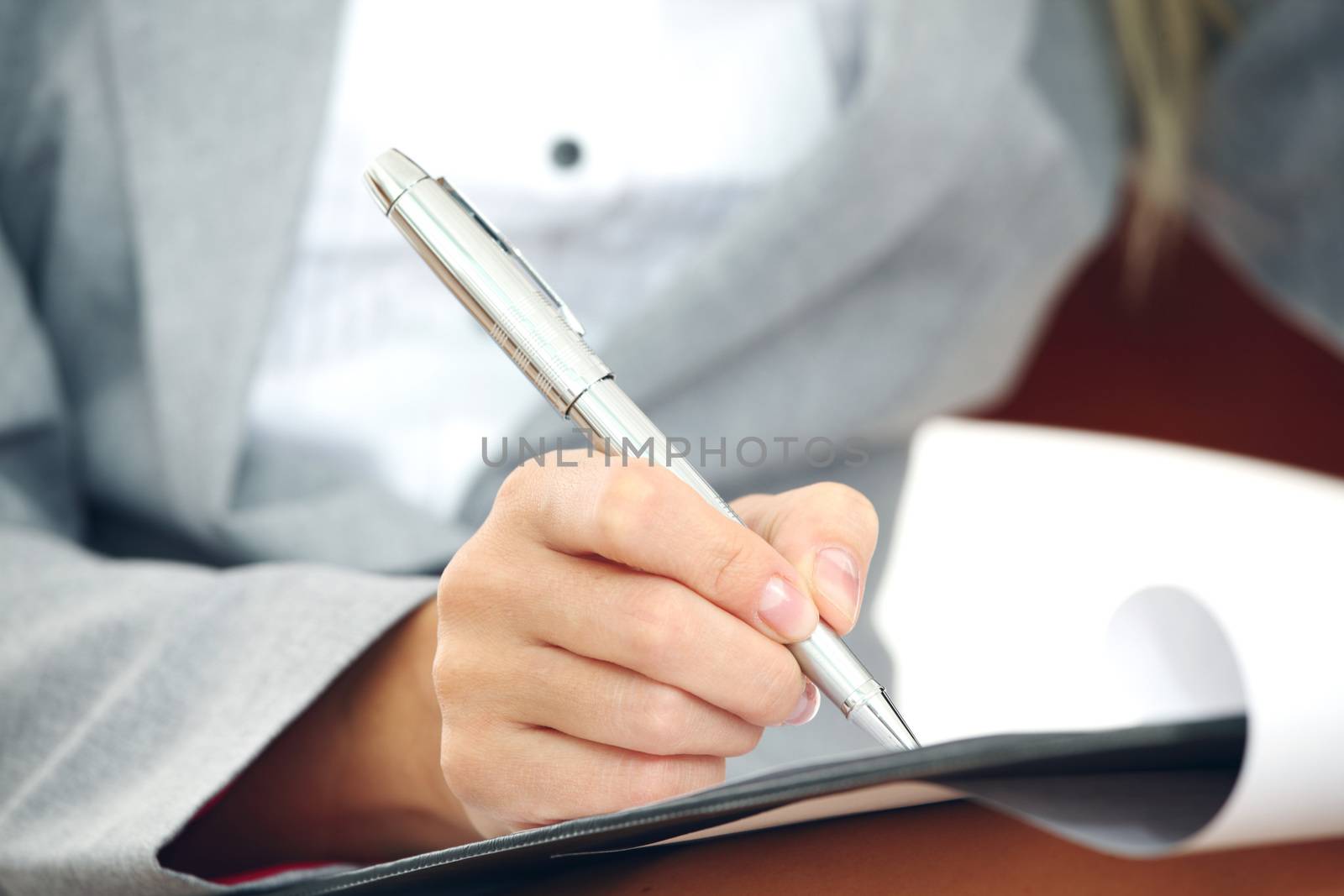 Business woman in suit writing notes with pen on document paper