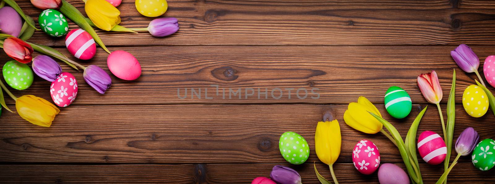 Hand-painted easter eggs with tulips on wooden background copy space for text