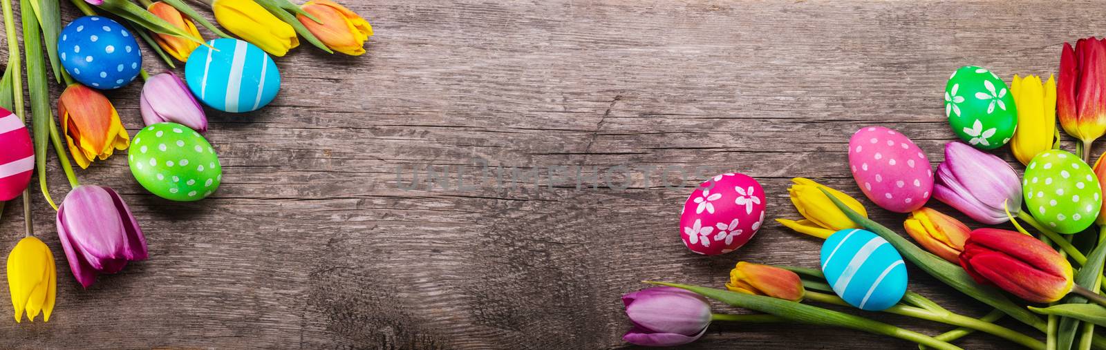 Hand-painted easter eggs with tulips on wooden background copy space for text