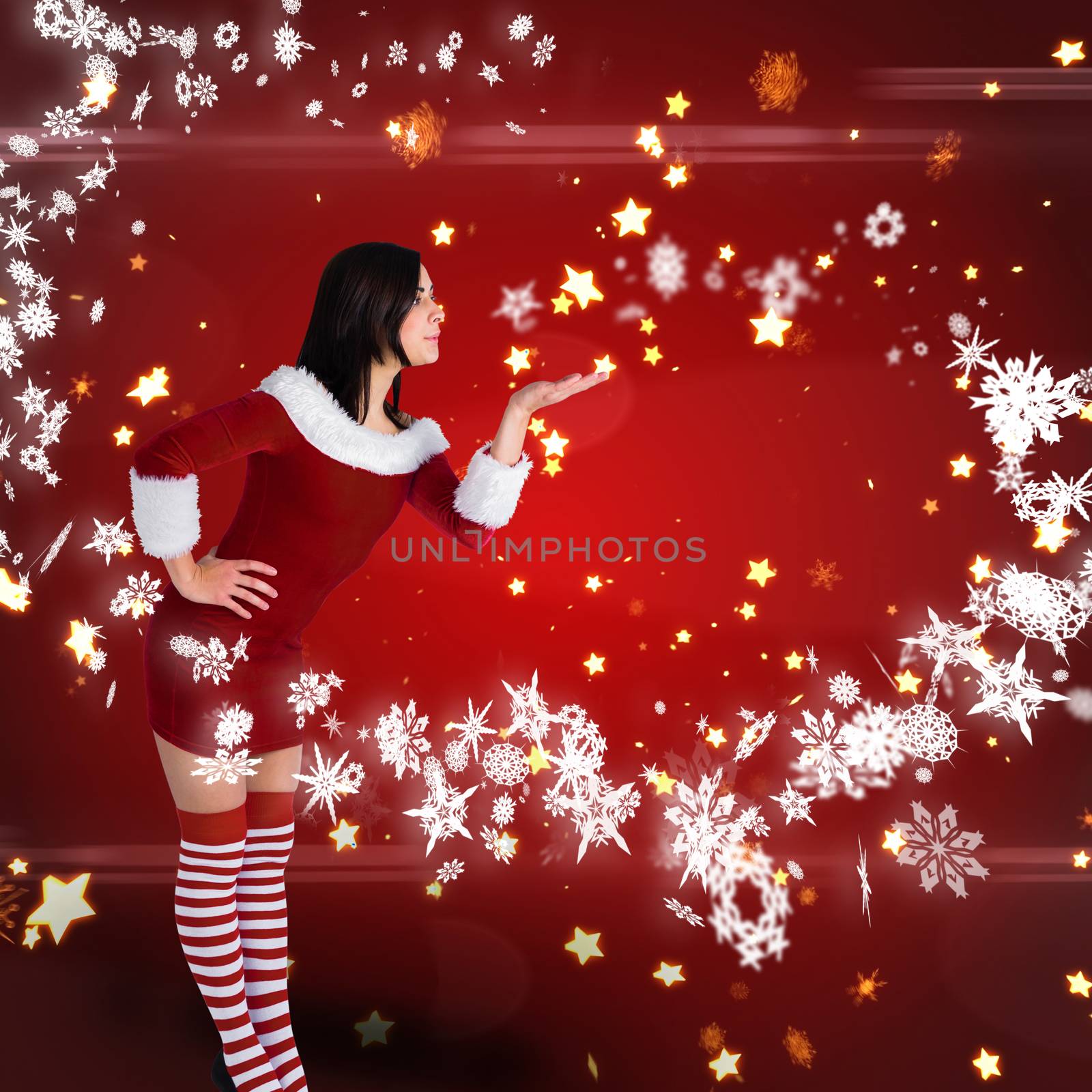 Pretty girl in santa outfit blowing against bright star pattern on red