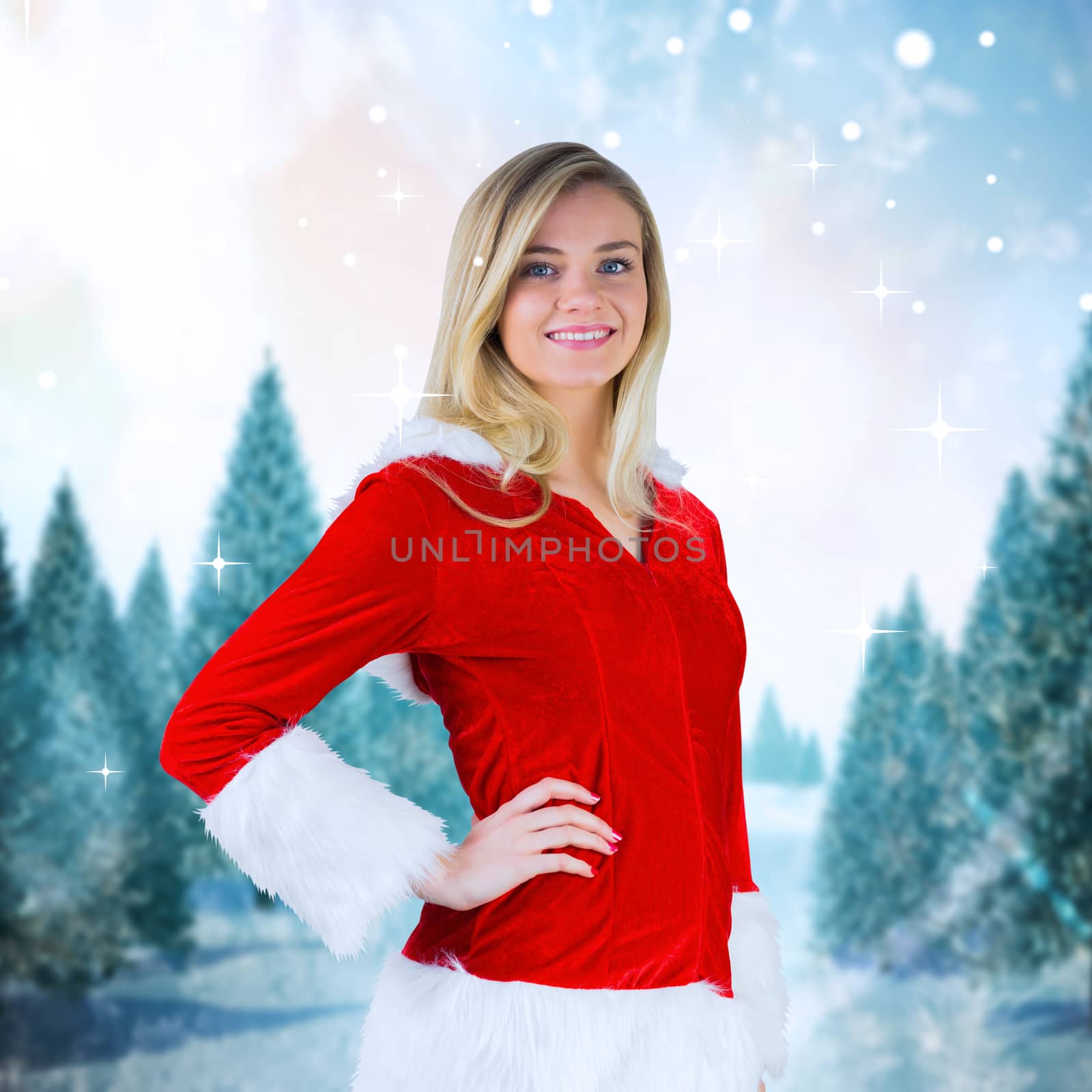 Pretty girl smiling in santa outfit against snowy landscape with fir trees