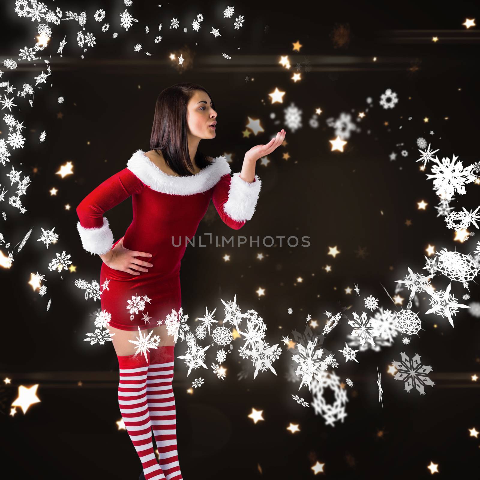 Pretty girl in santa outfit blowing against bright star pattern on black