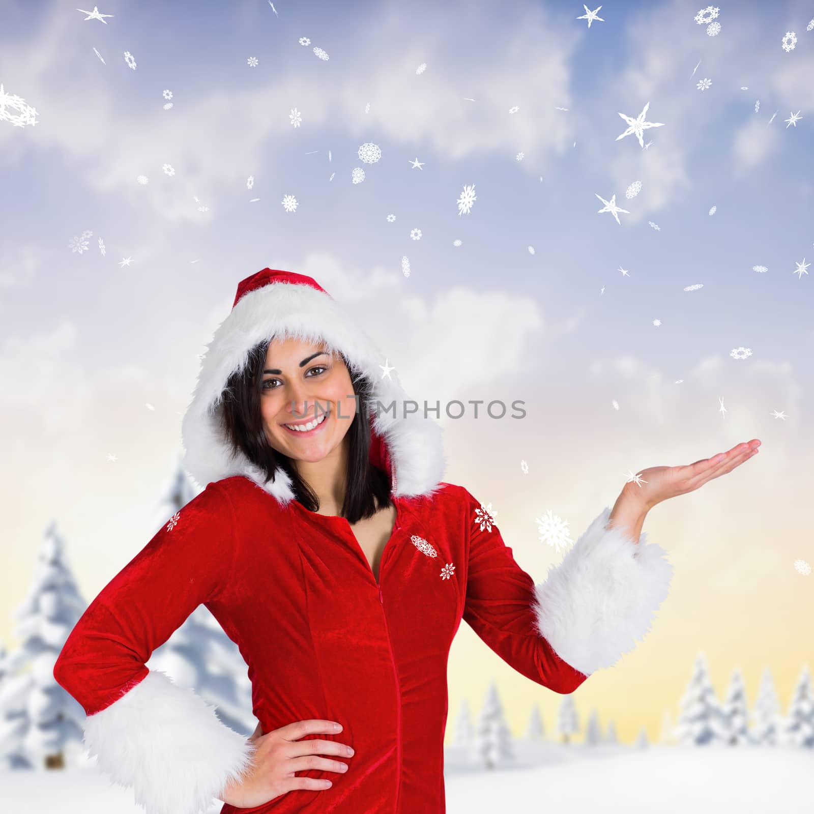 Pretty girl presenting in santa outfit against snowy landscape with fir trees