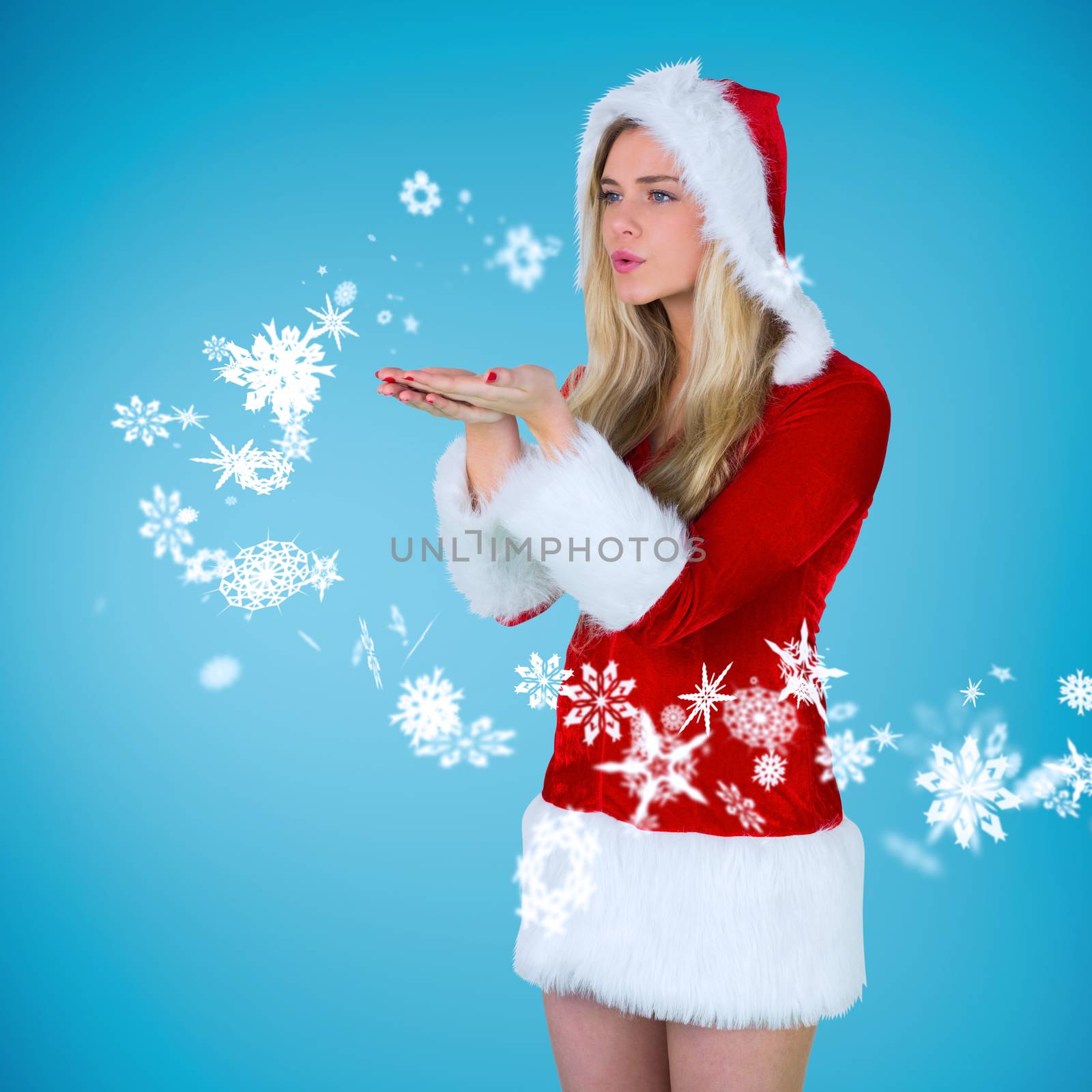 Pretty girl in santa outfit blowing against blue vignette