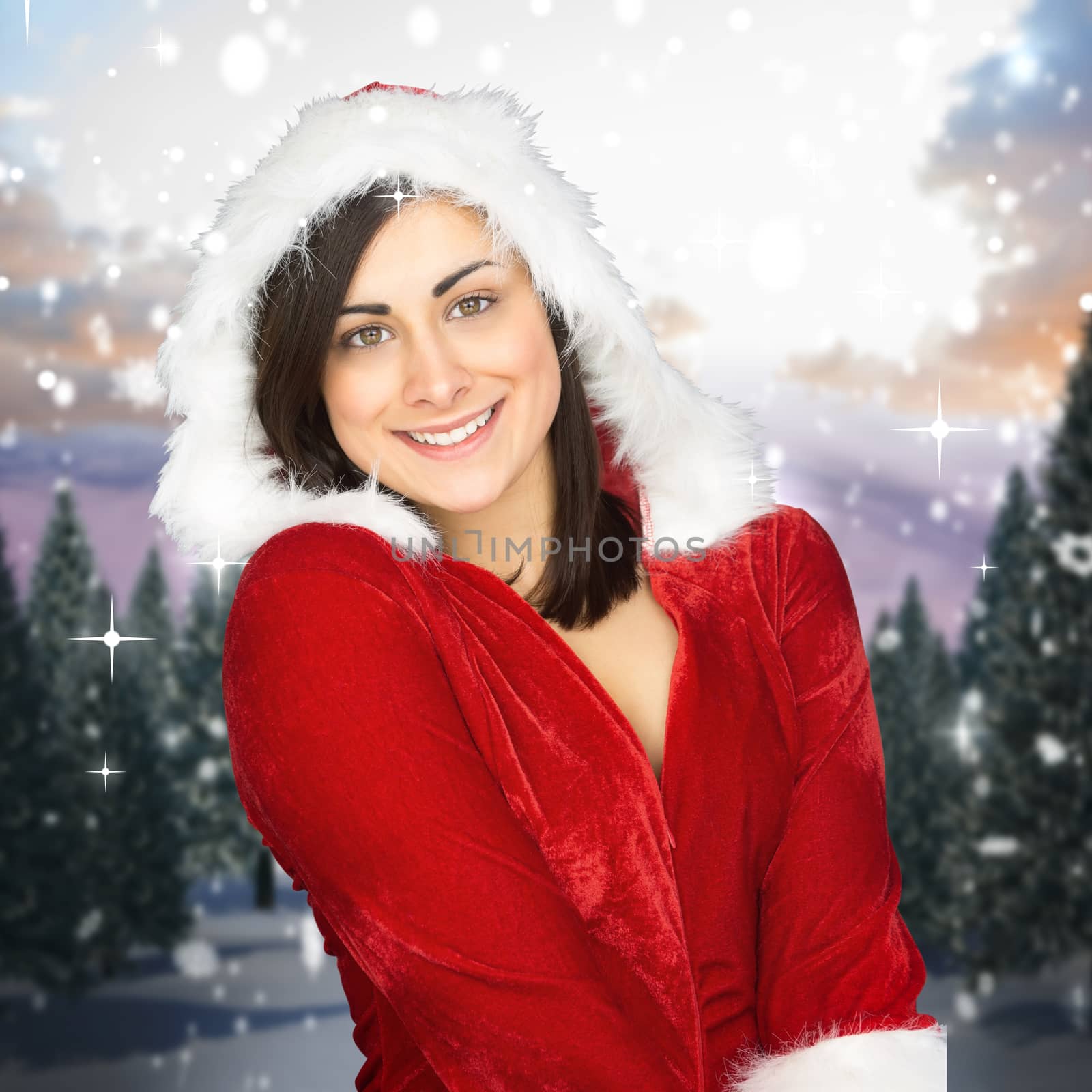 Pretty girl smiling in santa outfit against snowy landscape with fir trees