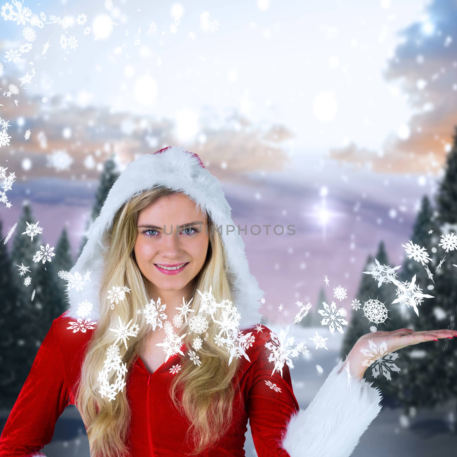 Pretty girl presenting in santa outfit against snowy landscape with fir trees
