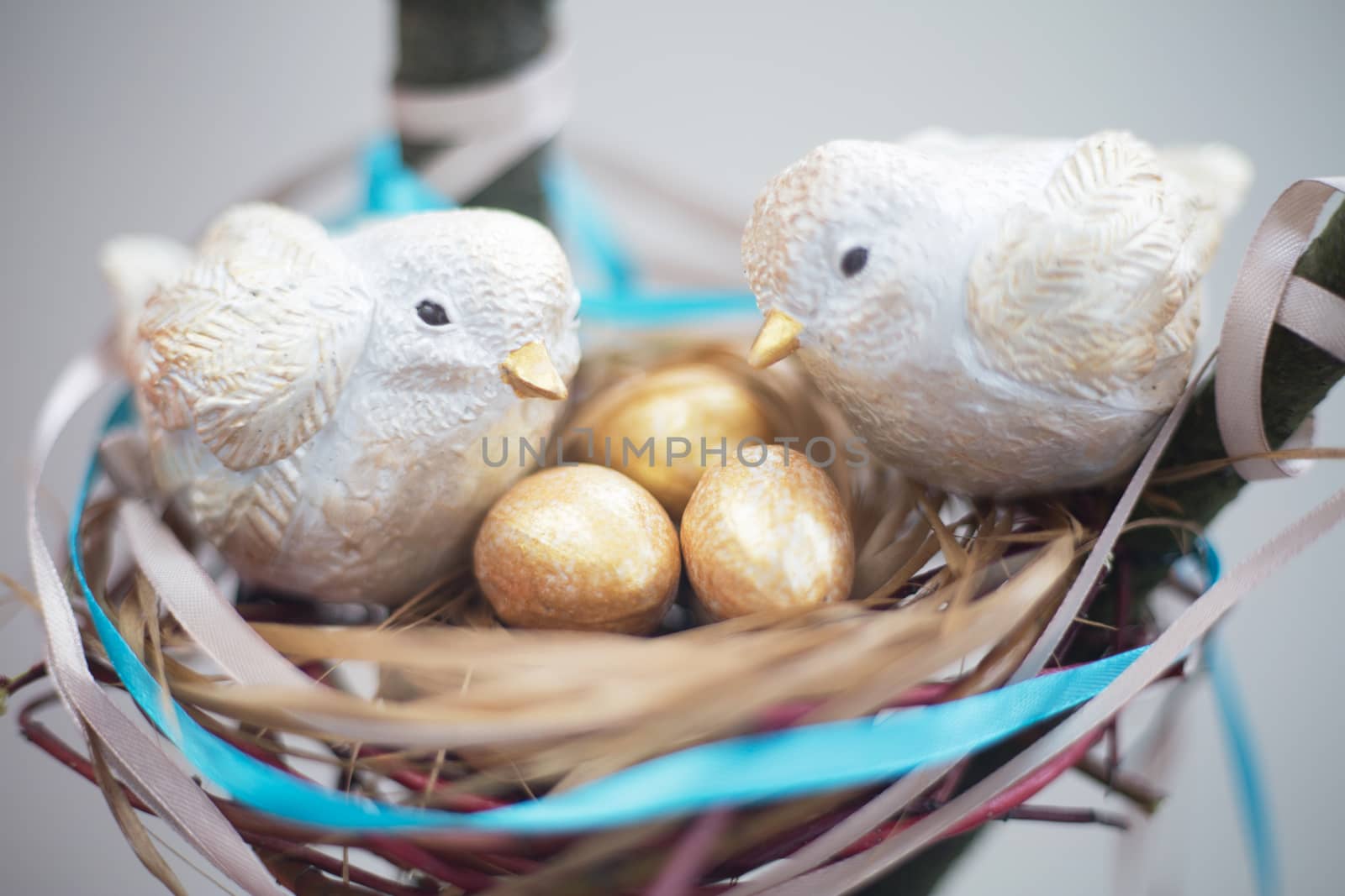 Two cute handmade small birds and their golden eggs in nest , parentind, care, easter concept