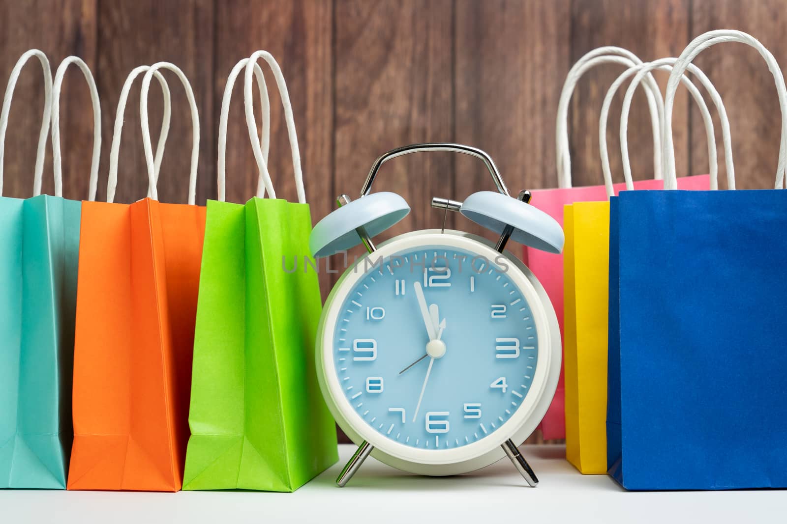 Blue alarm clock and colorful shopping bags for time to buy concept