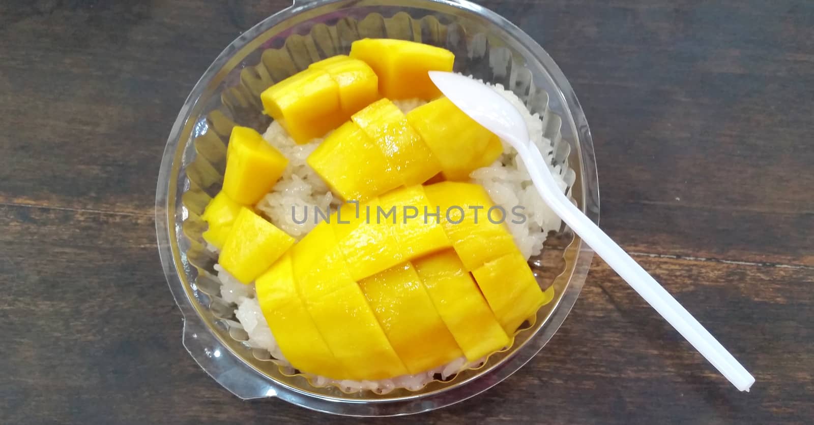 Thai mango and sticky rice  desserts on white dish with wooden background. Top view.