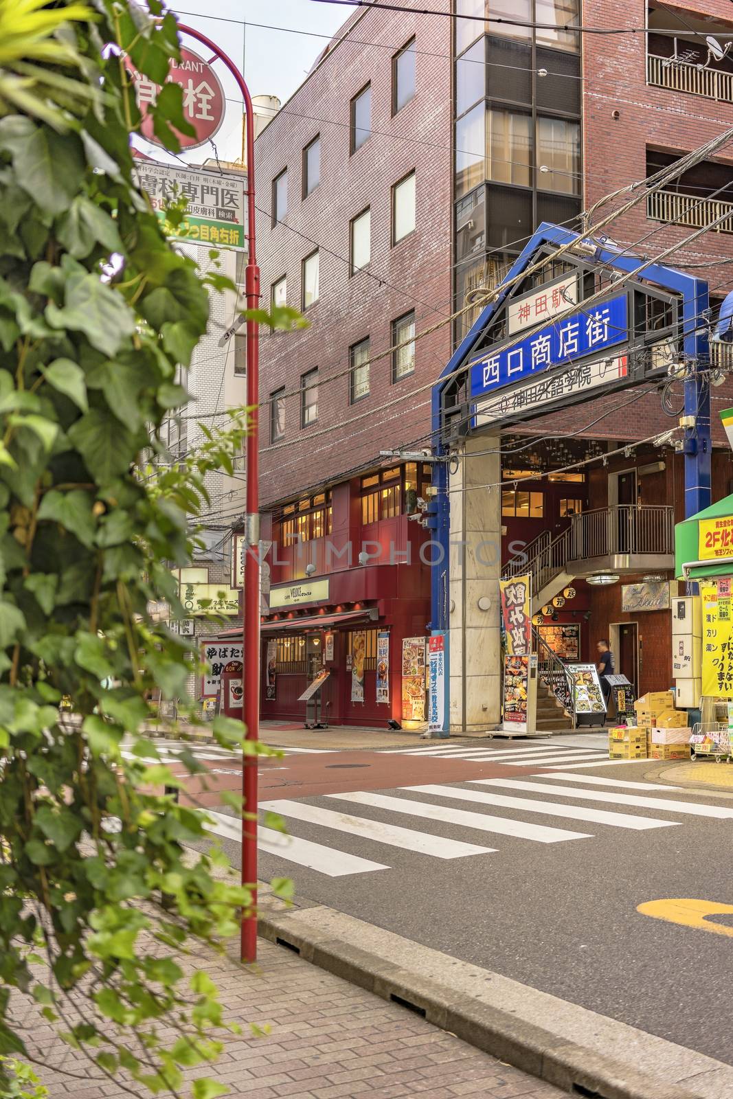 Blue metal entrance gate of the shopping street decorated with plants from the west exit of Kanda Station on the Yamanote Line. The street extends over 300 meters and has no less than 100 shops.