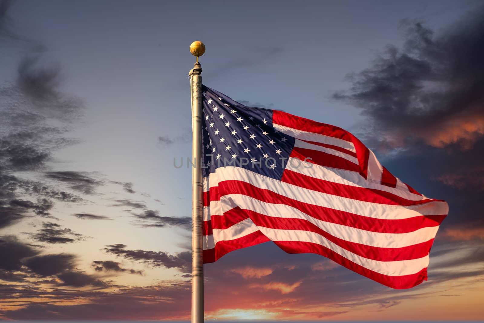 Red White and Blue American Flag in Breeze at Sunset by dbvirago