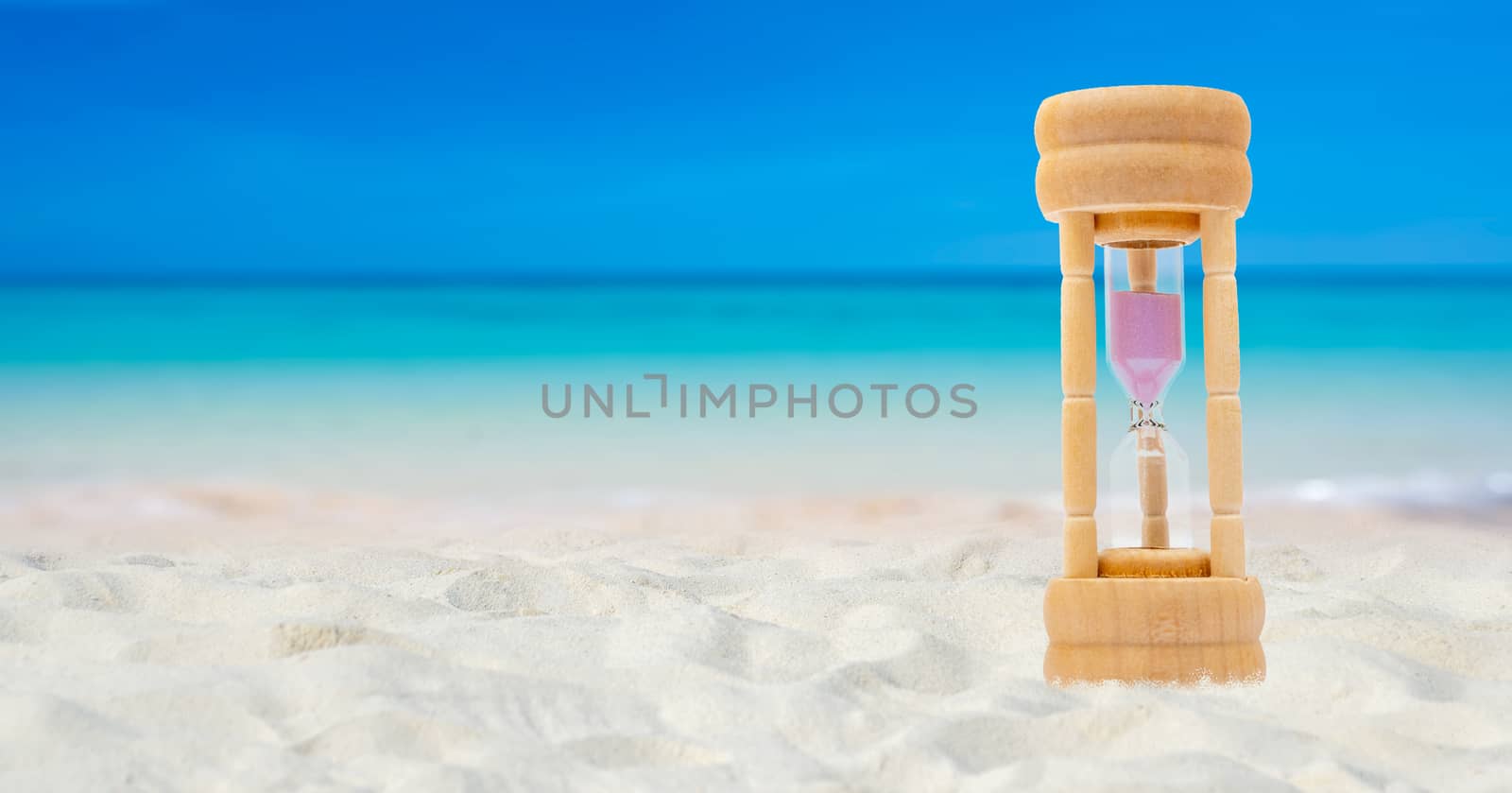 Hourglass set on a white sand background sea background, time concept