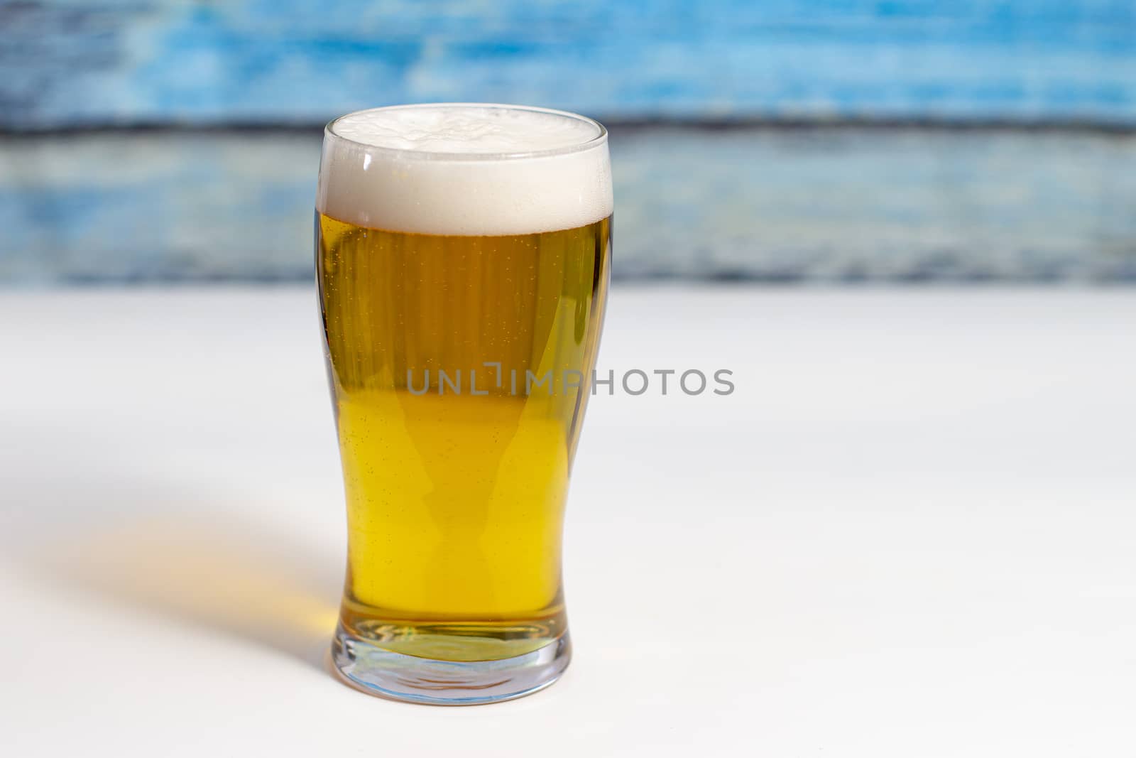 Pint of beer on a white table with a colourful wooden wall by oasisamuel