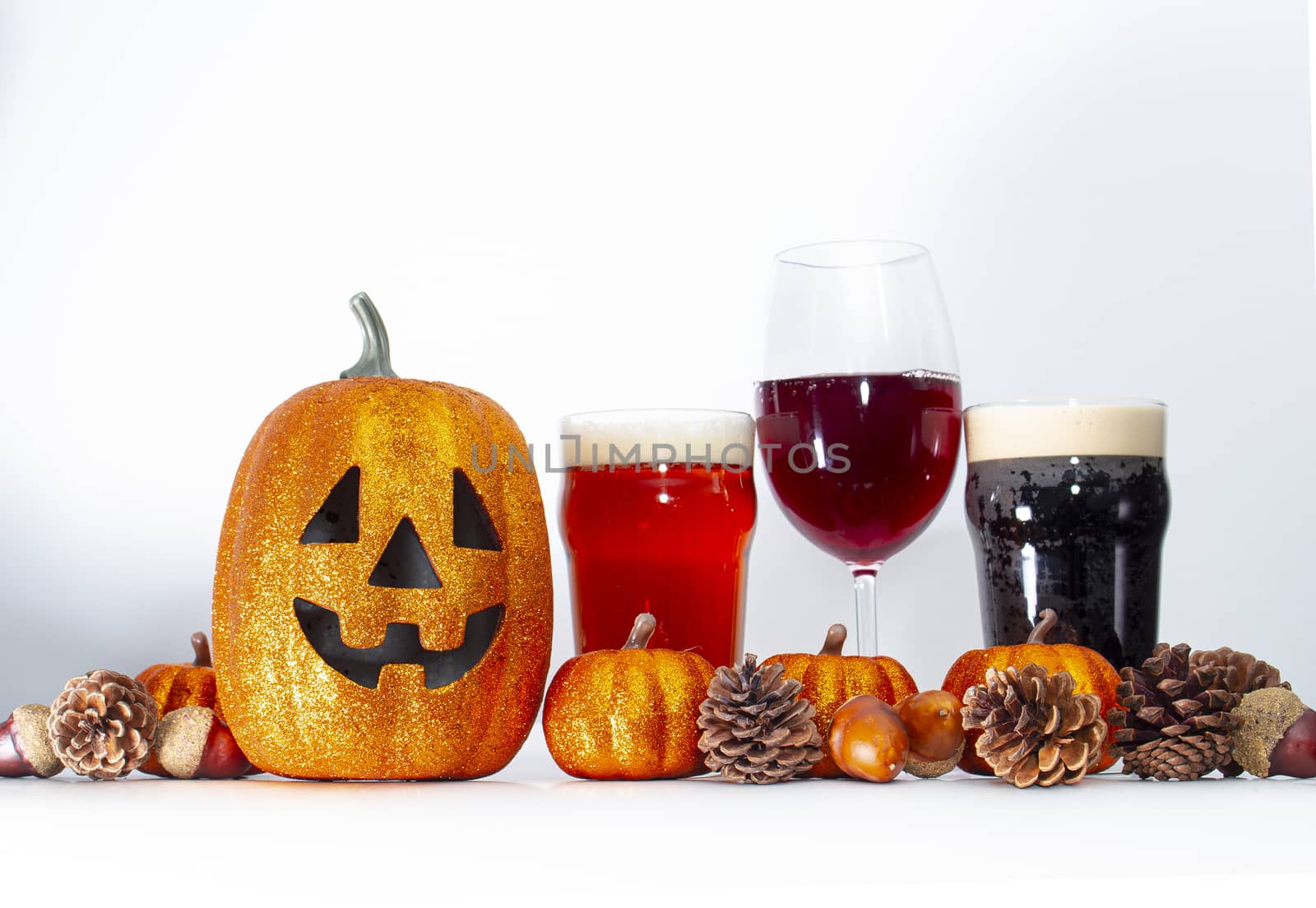 Pumpkin with alcoholic drinks with ornaments around on a white background