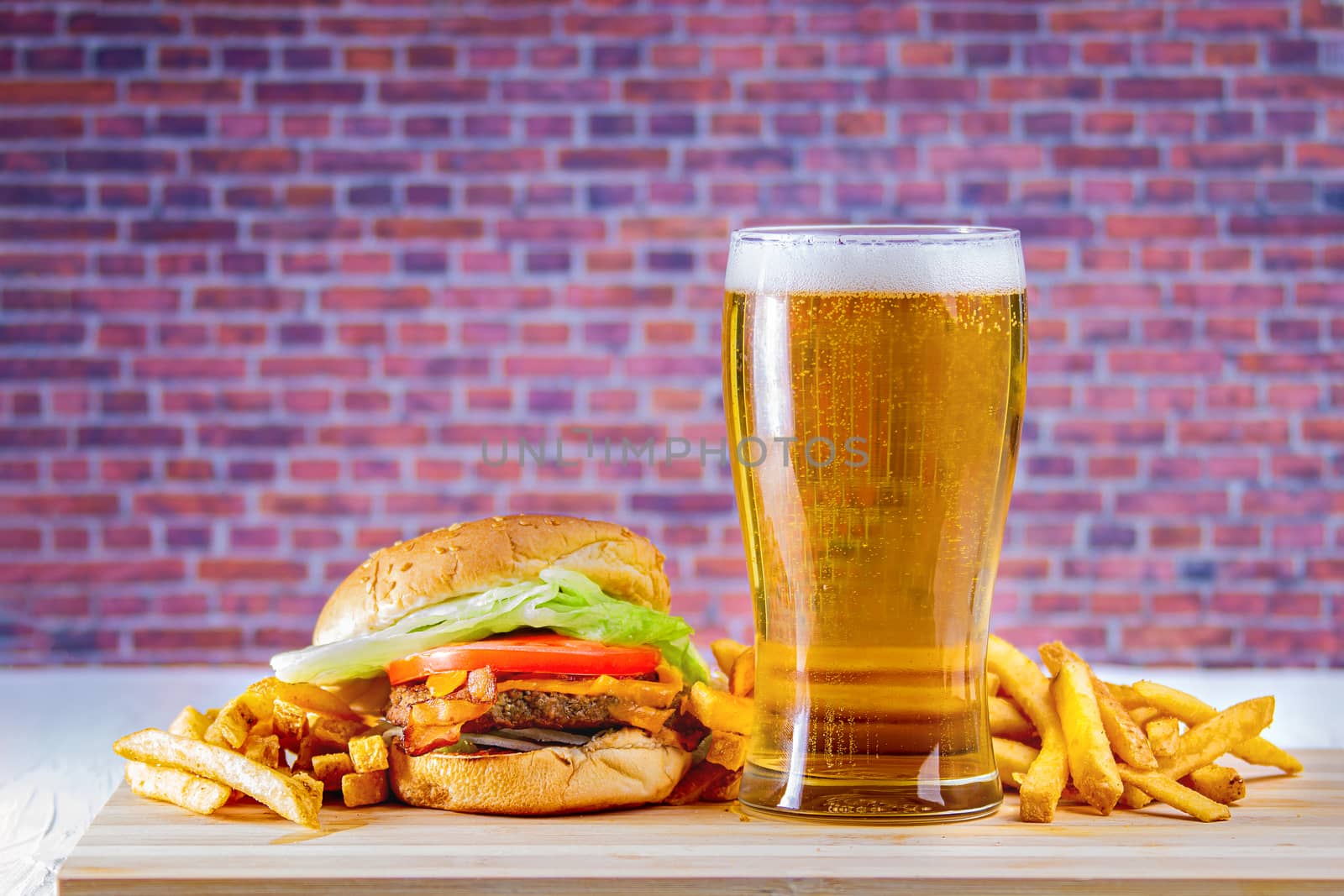 Glass of beer and fries on wooden table