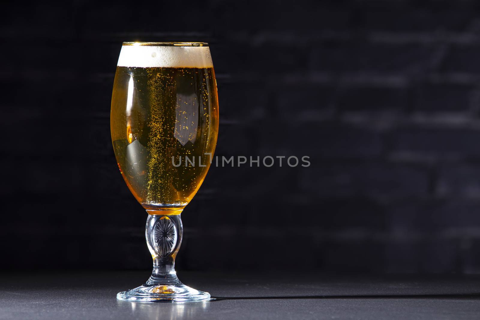 A cups of Stella Artois full of beer with a black brick background
