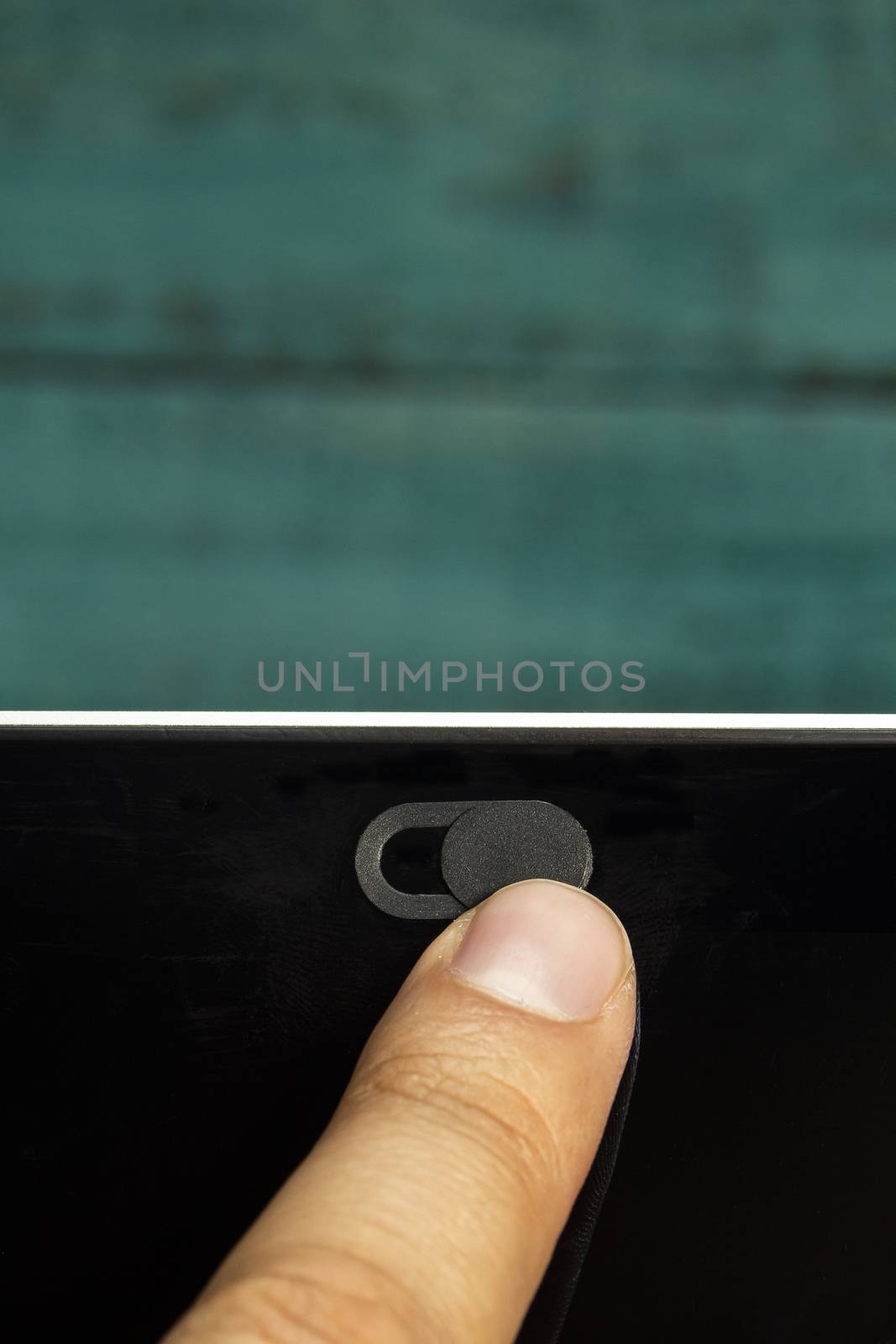 Camera Privacy Cover Slide by a finger with a green wooden wall. by oasisamuel
