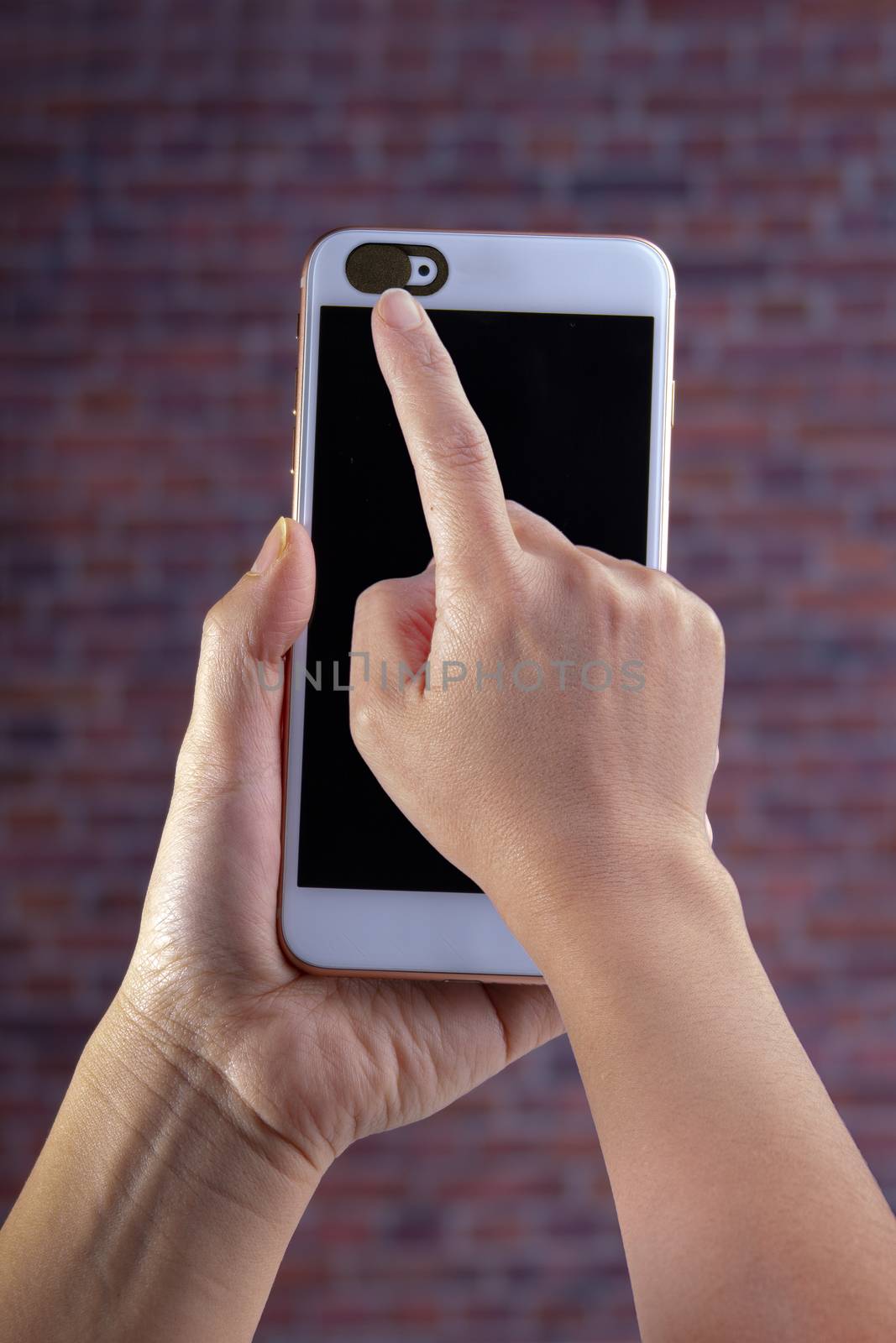 Smart phone camera privacy cover slide, for front camera cover for smart device hand hold on a red brick background